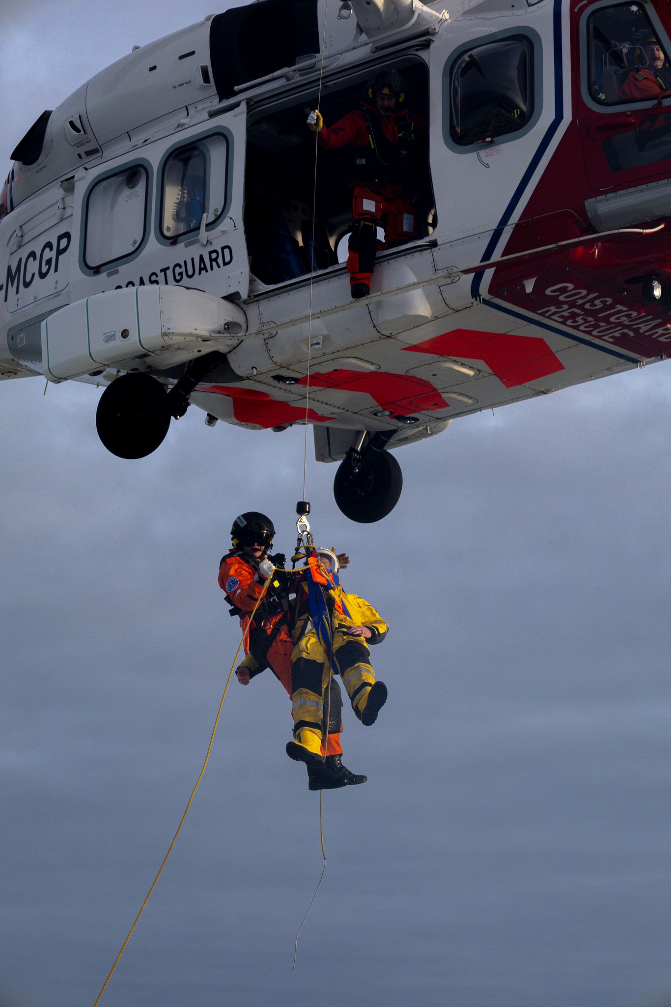 two people hanging from helicopter