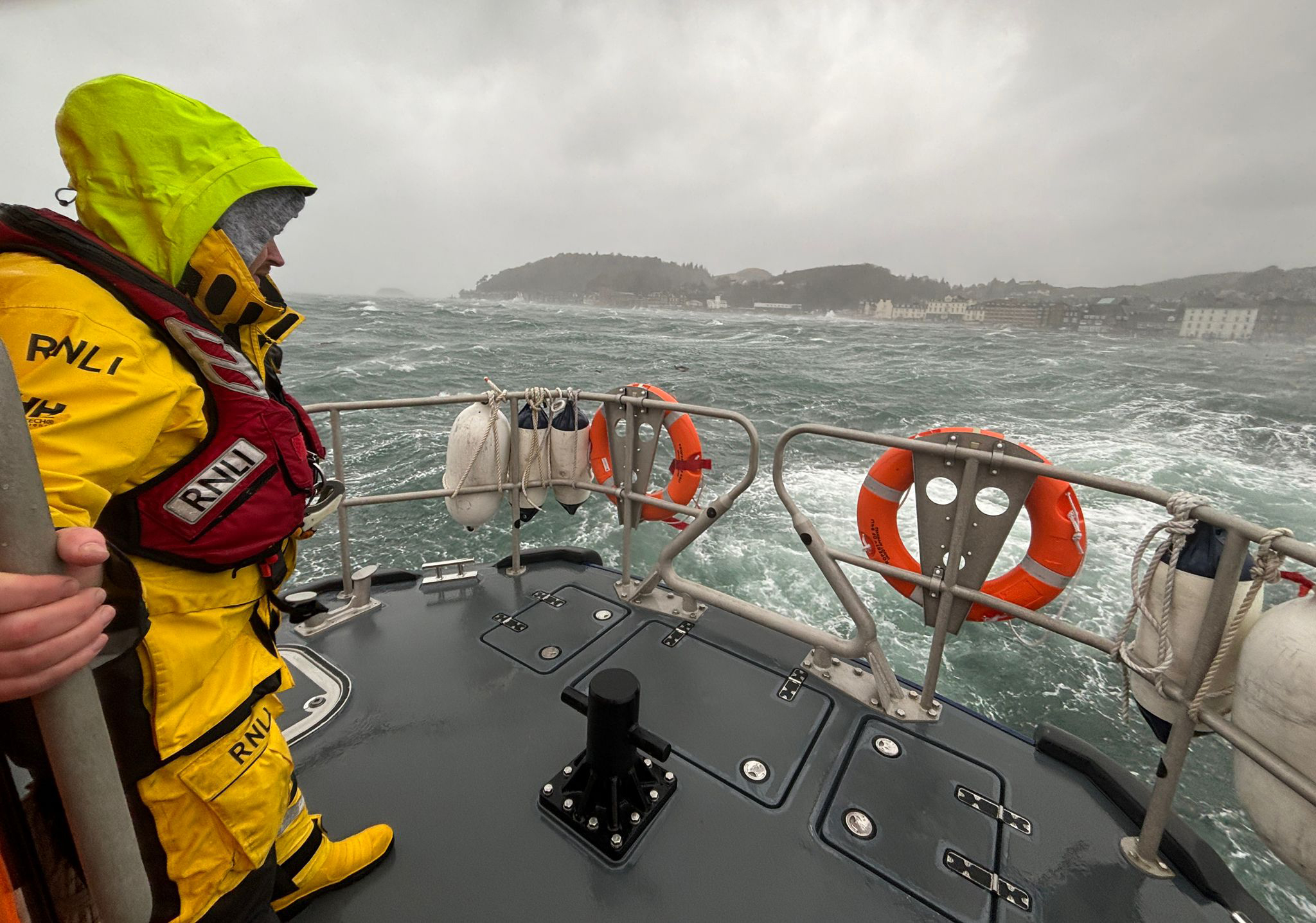 A crew member stands close to the superstructure of the Shannon Class lifeboat in heavy seas