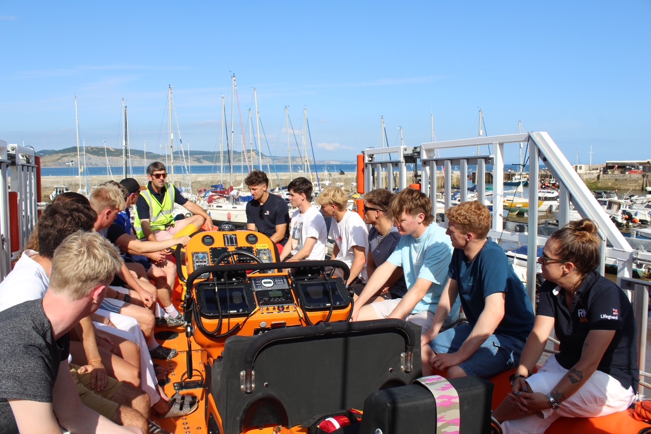 Lifeguards seated on the lifeboat being briefed by Helm in yellow jacket