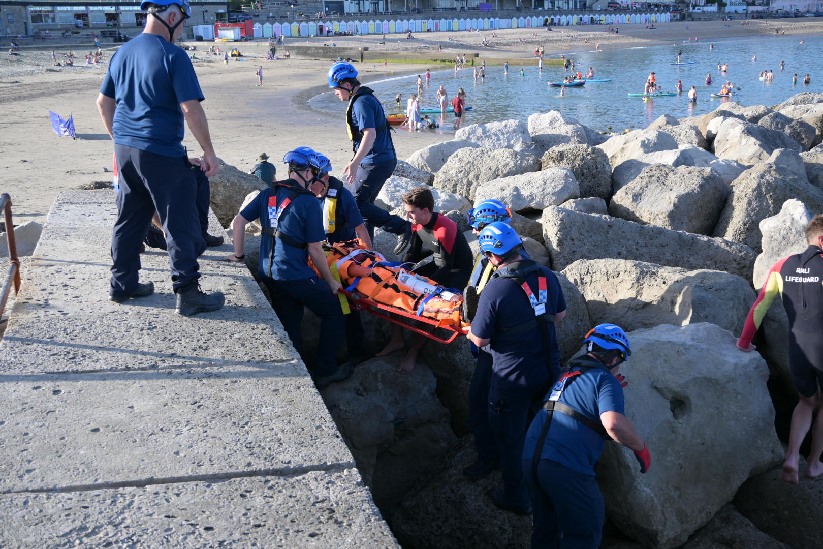 Team of people carry person on stretcher across rocks