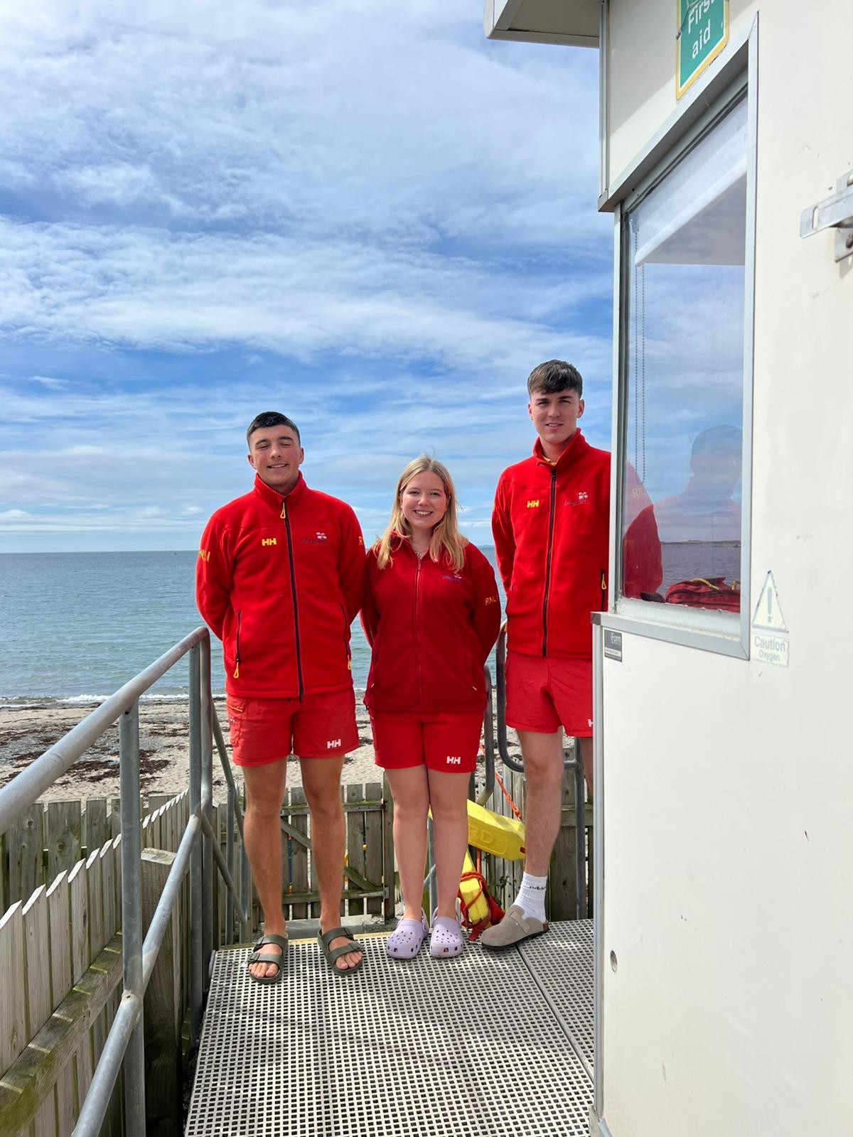 RNLI Lifeguards Catriona, Evan and Adam standing by the hut 