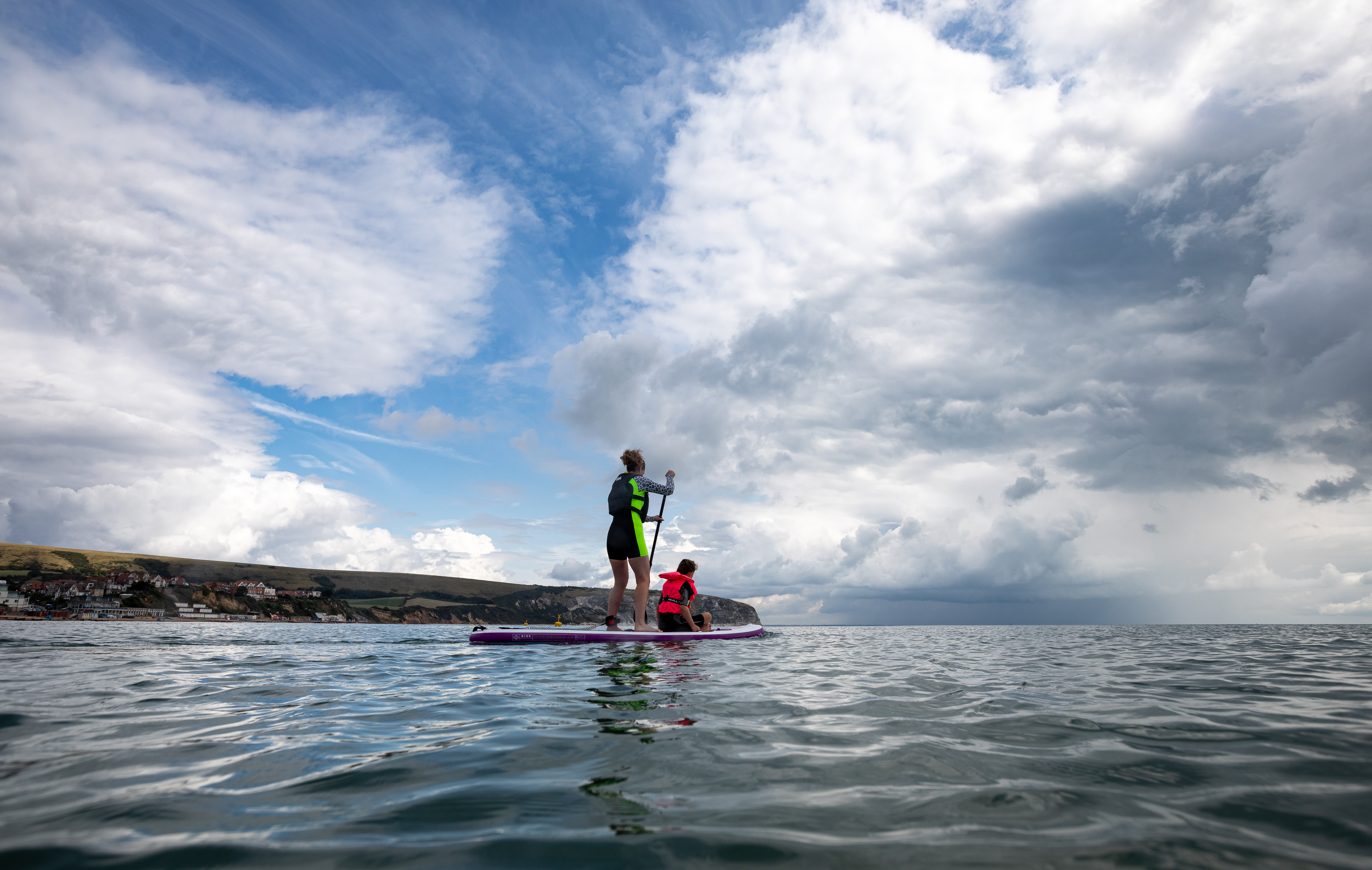 Stand up paddleboarders (SUP) going for a paddle at Swanage beach on open water