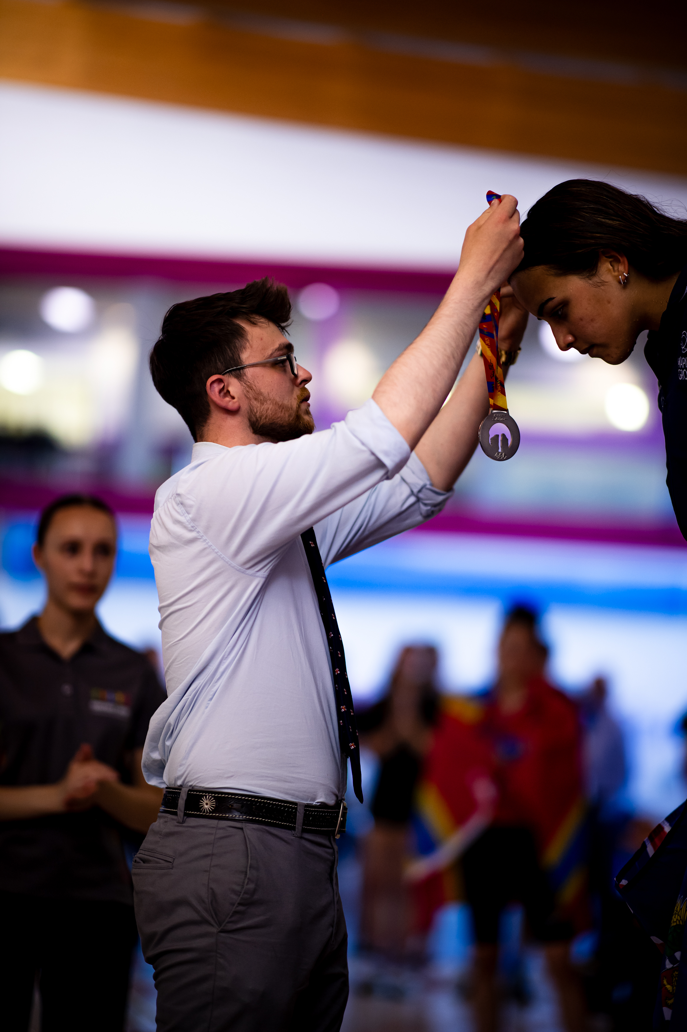 Crew members hanging medal around neck of athlete