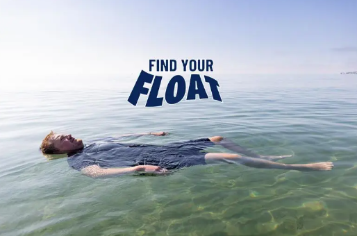 Man floating in open water with the words find your float written in blue above him
