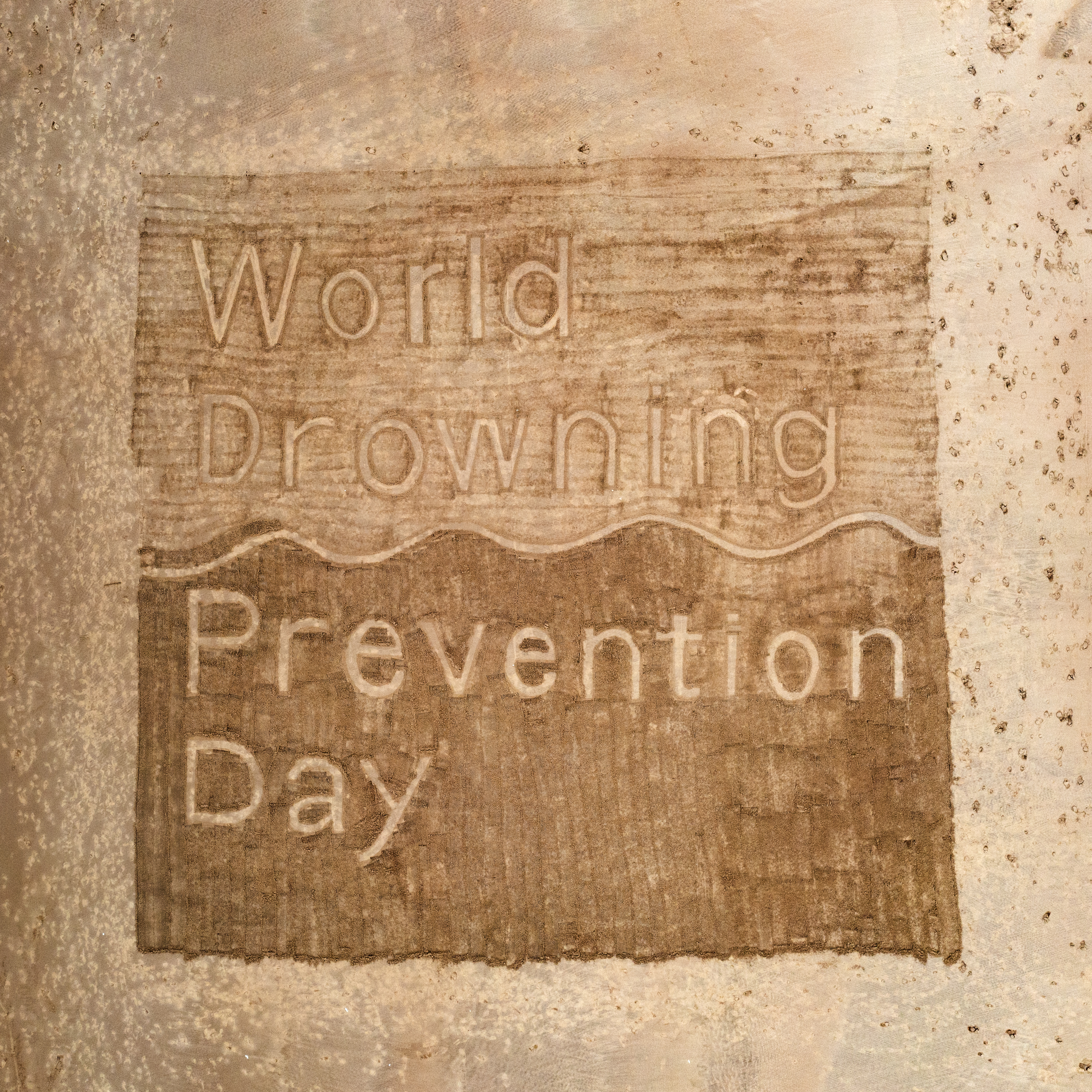 World drowning prevention day sand art. words written in sand 