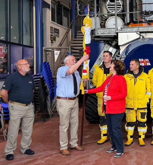 A lady presents a furled RNLI flag