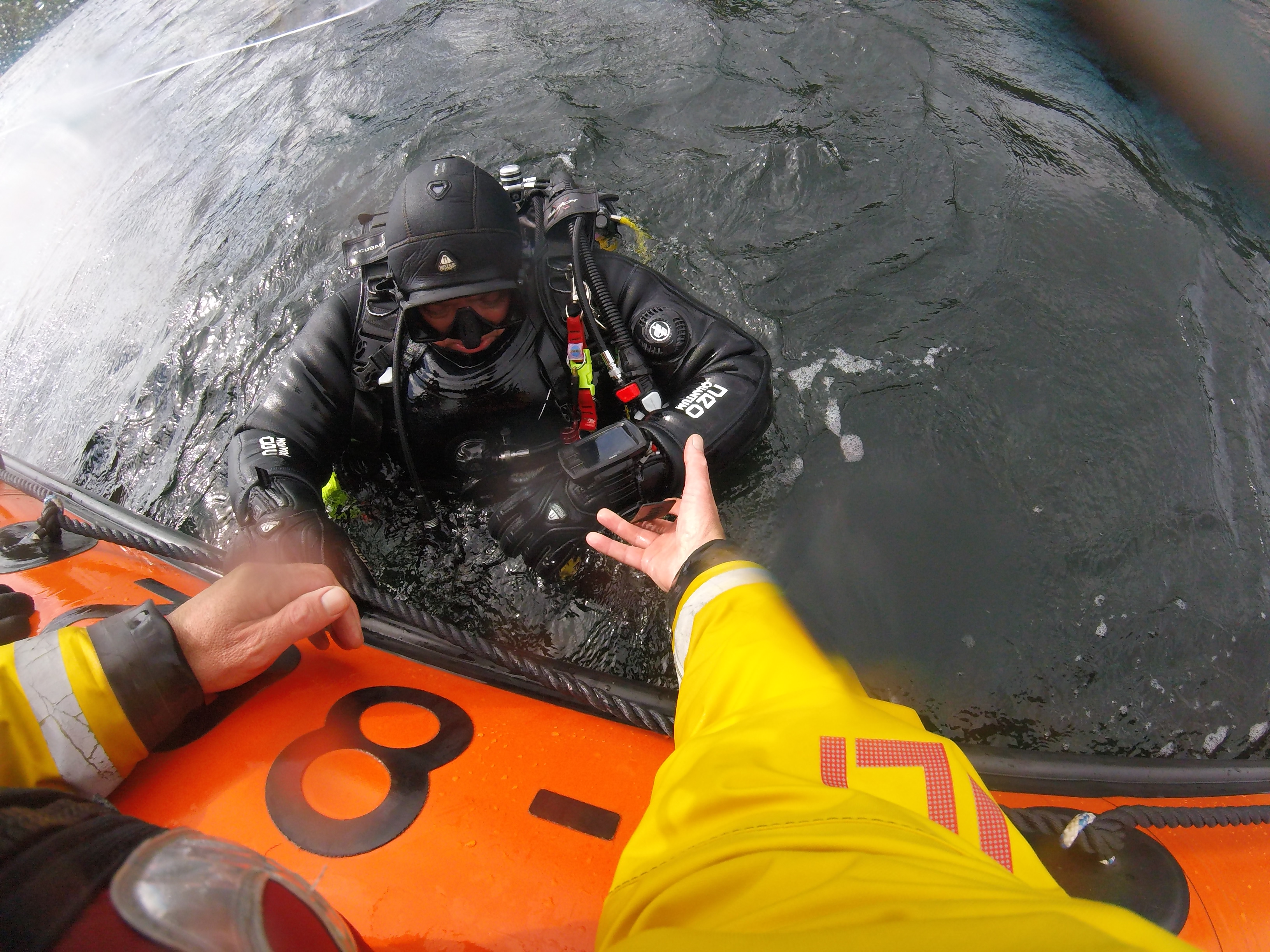 RNLI crew reach out to assist a diver from the water onto the lifeboat