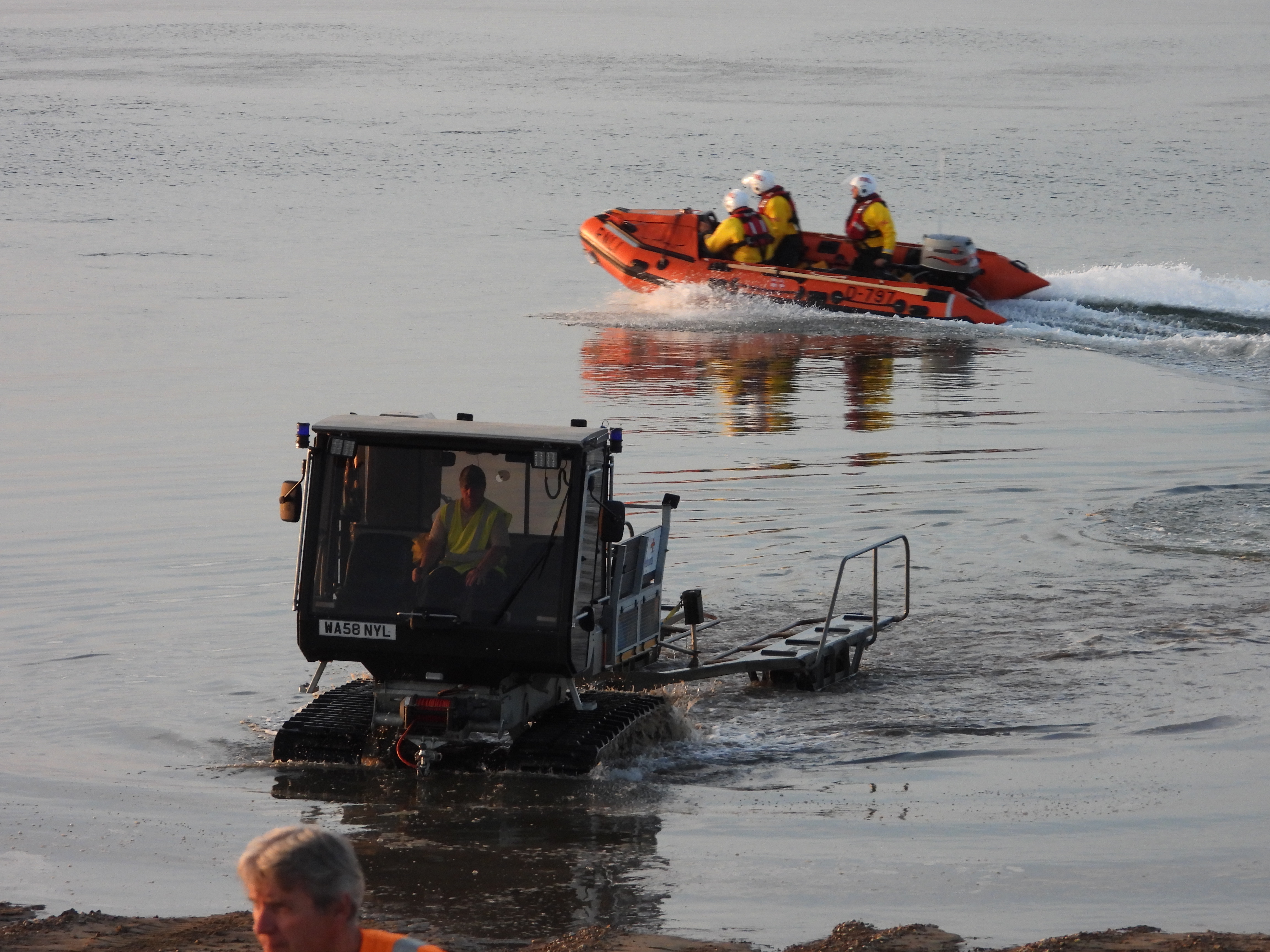 Wells RNLI D class lifeboat and launching and recovery vehicle launching inshore lifeboat in water at sunset