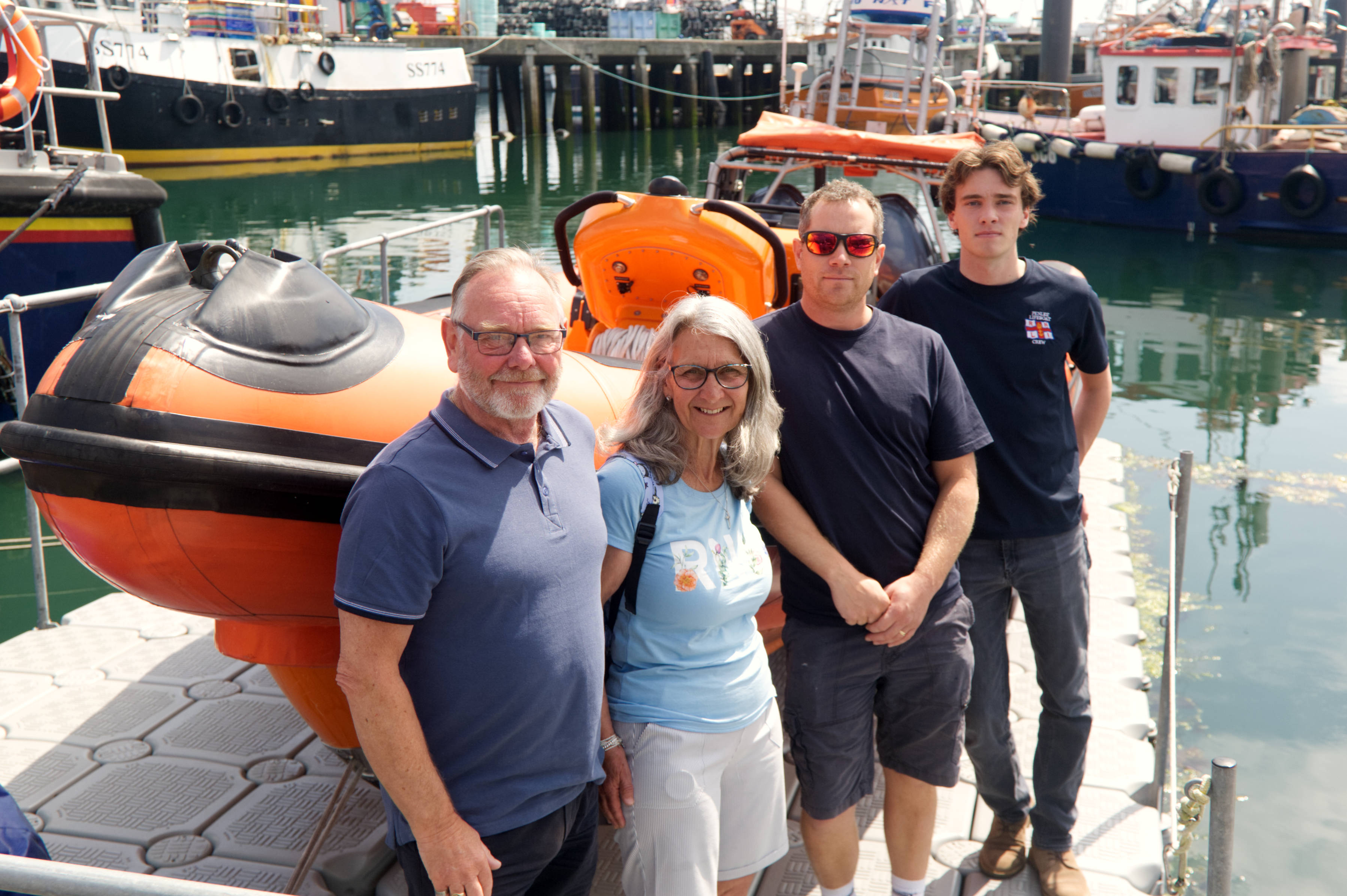 Picture shows four people standing beside a lifeboat