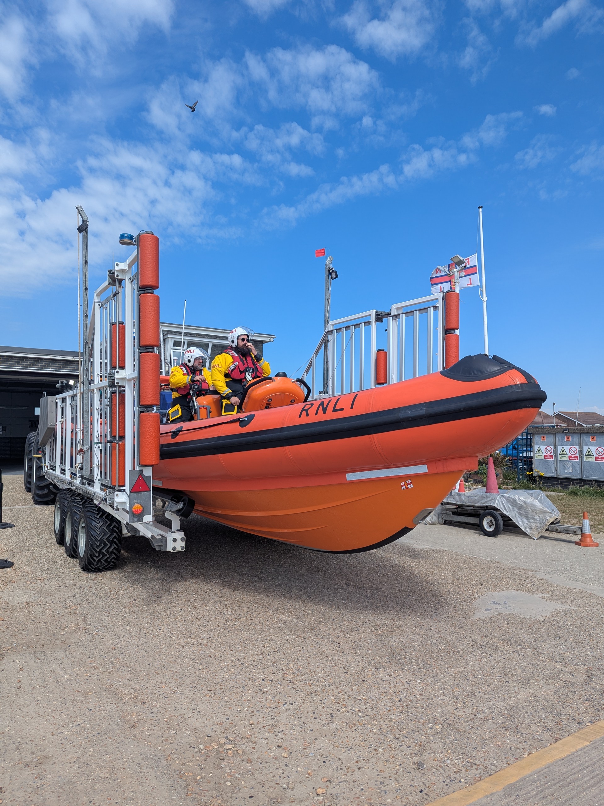 Orange lifeboat preparing to launch with crew members in bright yellow RNLI dry suits