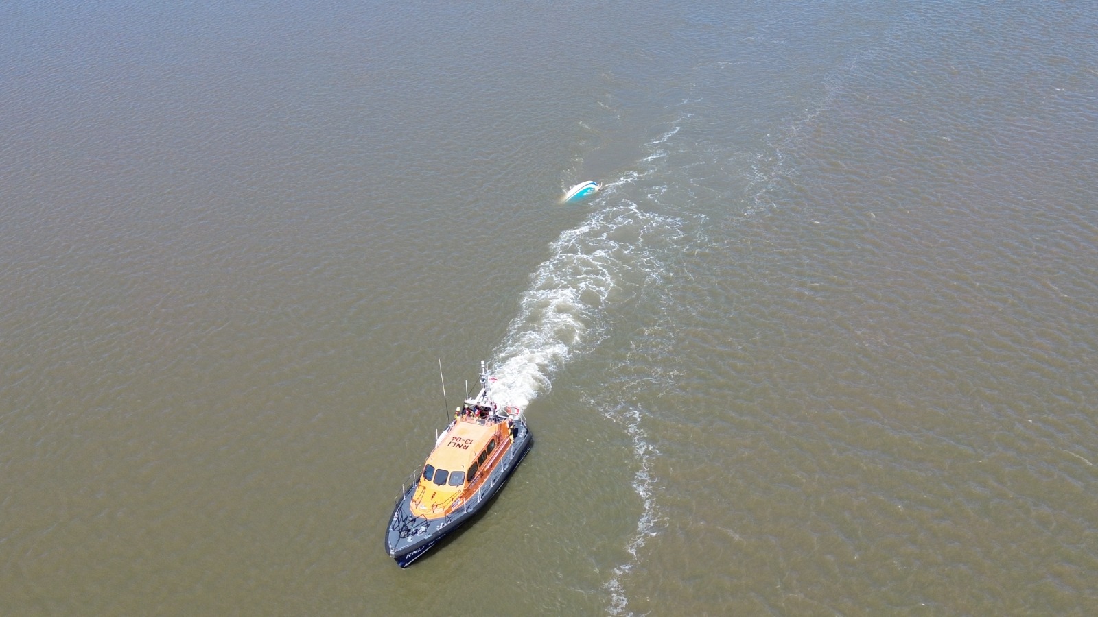Shannon-class lifeboat 10-04 Storm Rider towing the hull of the casualty yacht behind her