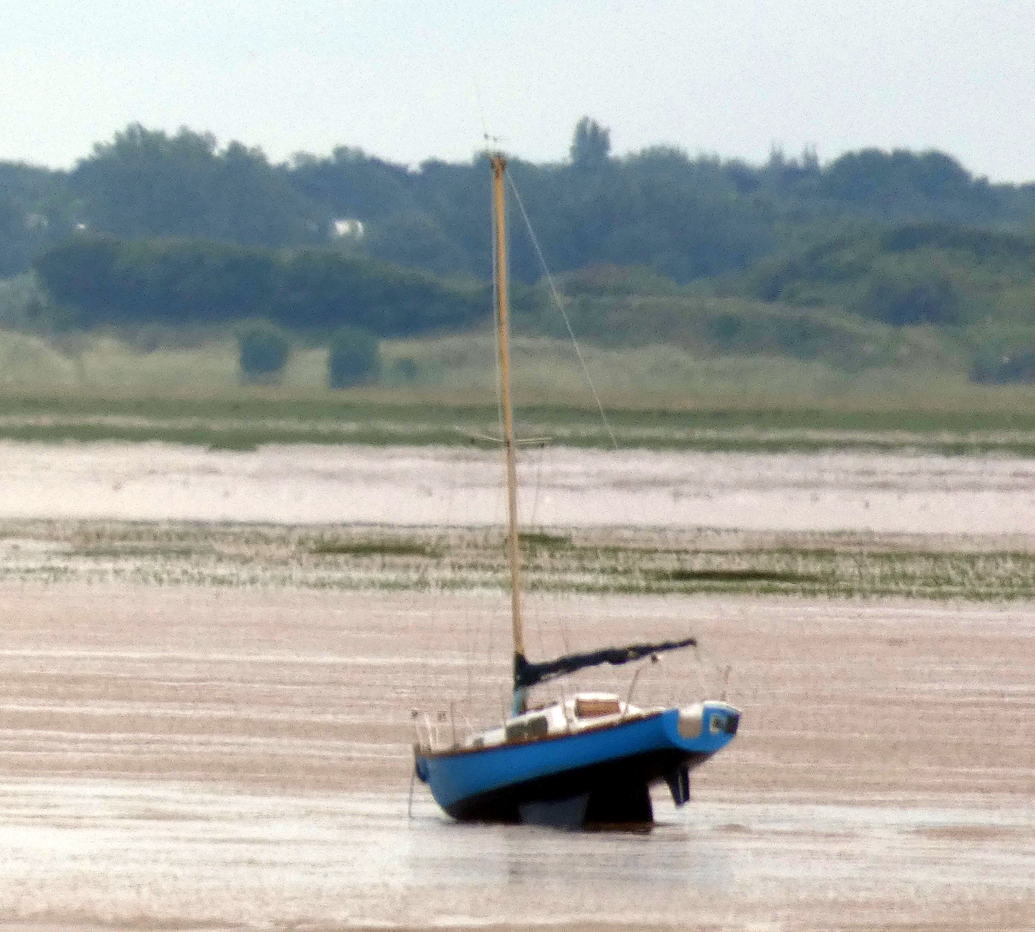 A yacht is aground and lying head down on mud
