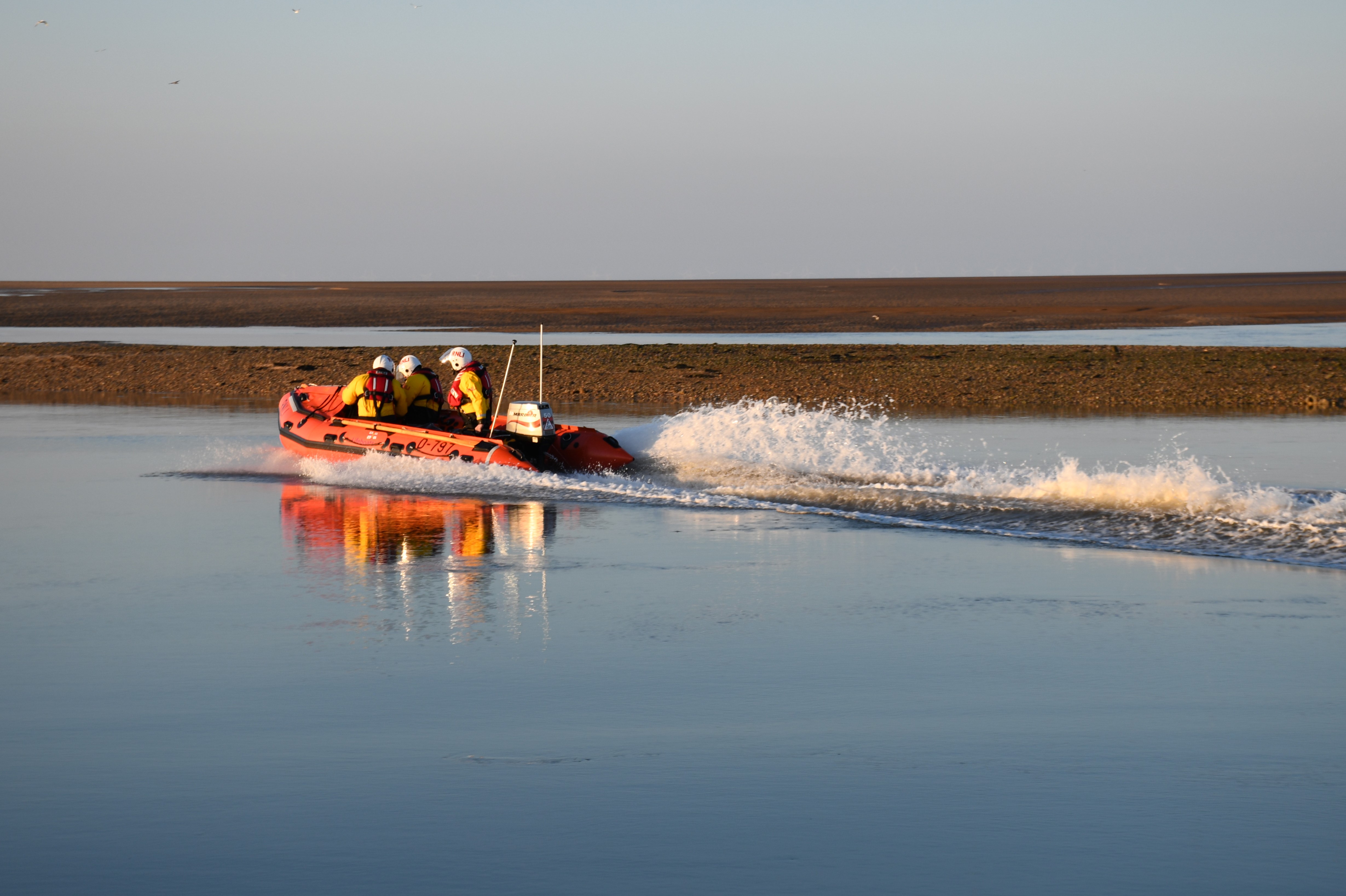 D class lifeboat D-797 searching shore for missing person with crew of three calm waters
