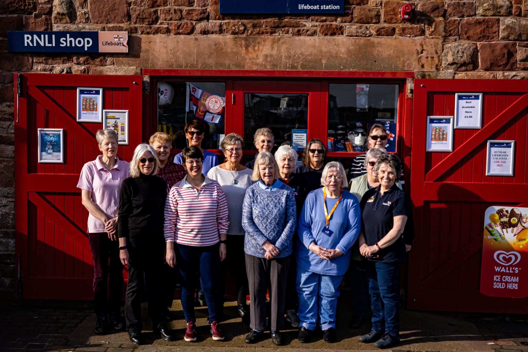 Fourteen women outside shop.