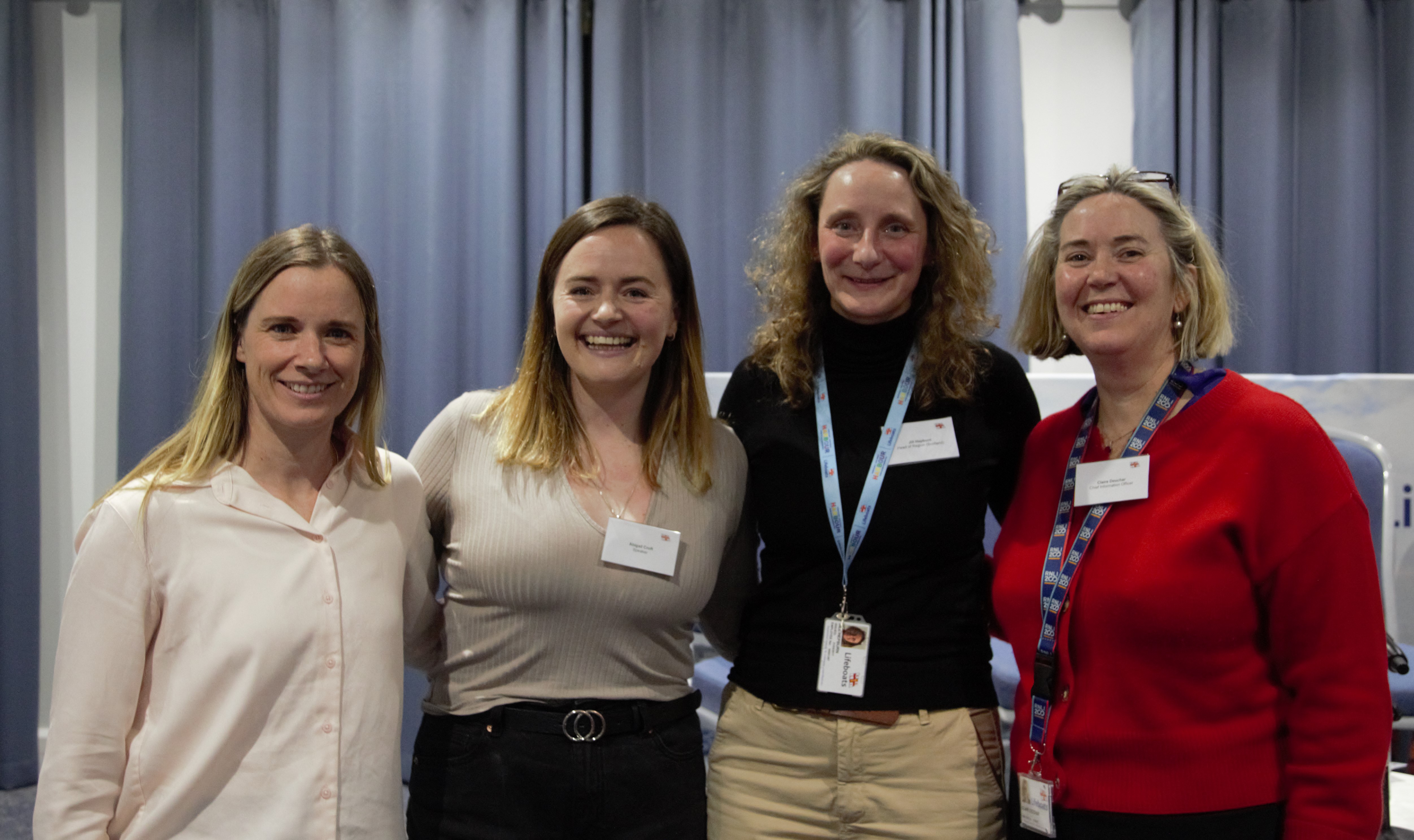 Four women stand together and look at the camera. 