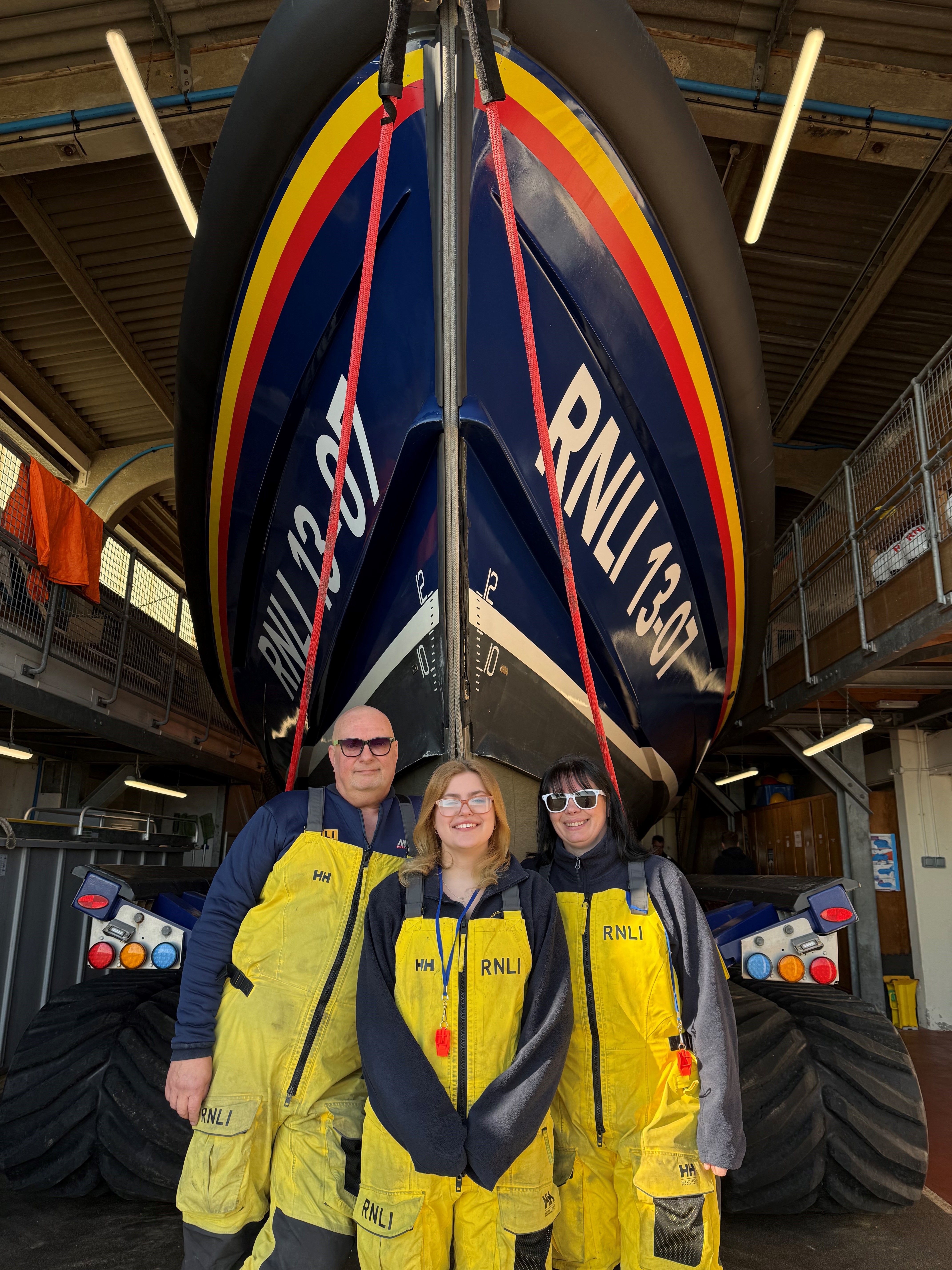 Three crew members standing in front of the lifeboat