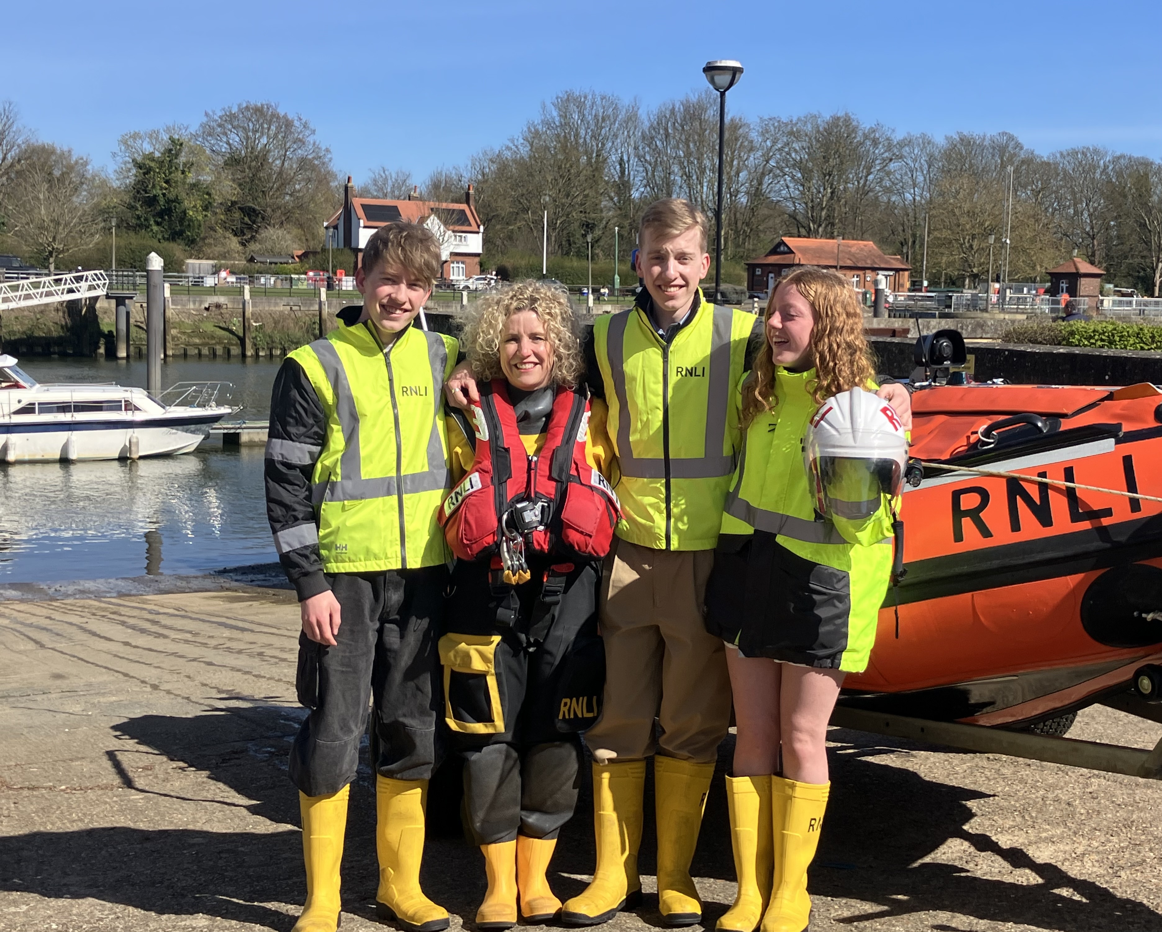 Mother in RNLI kit with three children in front of D Class lifeboat