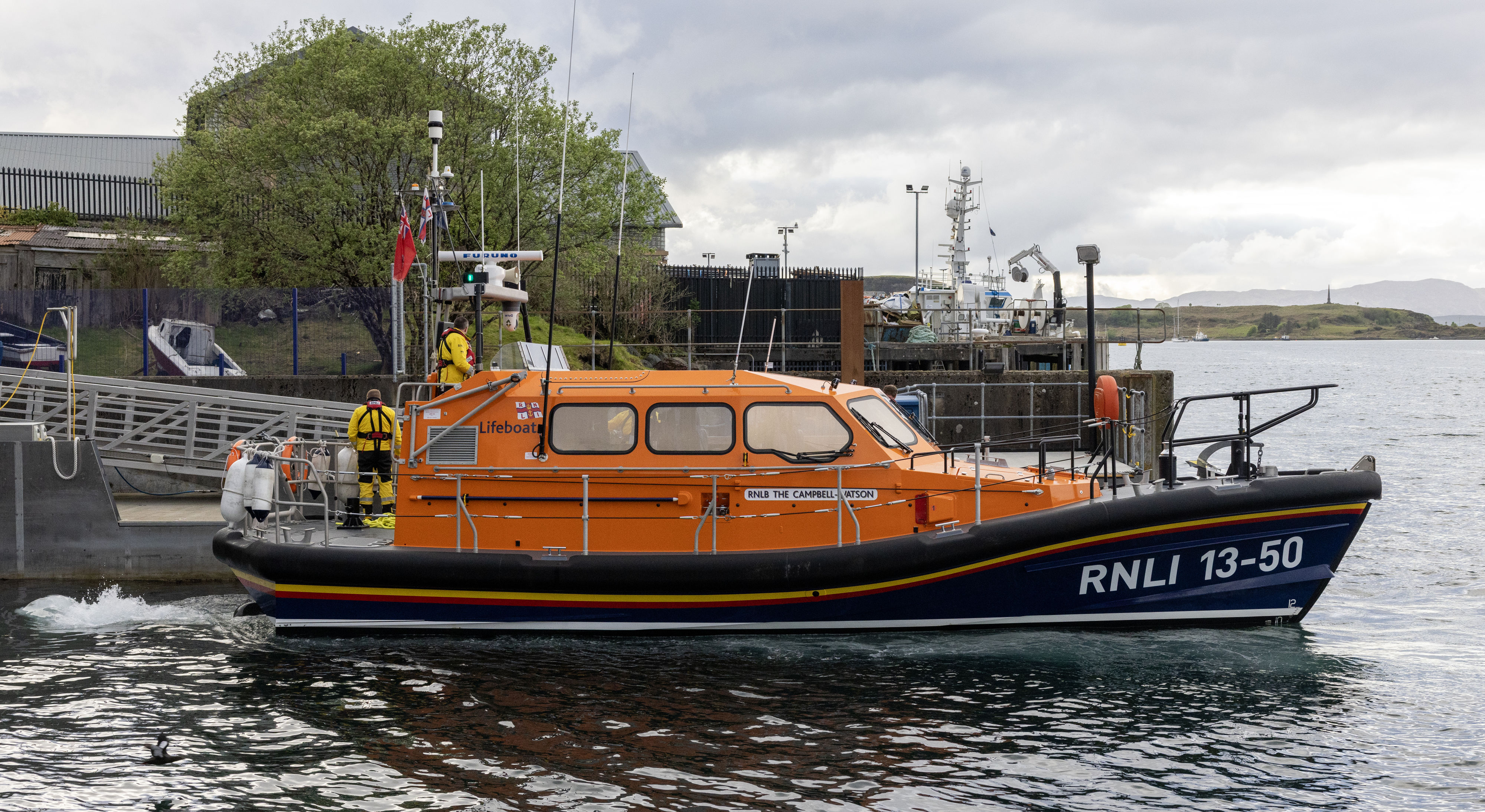 The Shannon class lifeboat manoeuvring close to the pontoon with the yellow-clad crew working to secure the vessel