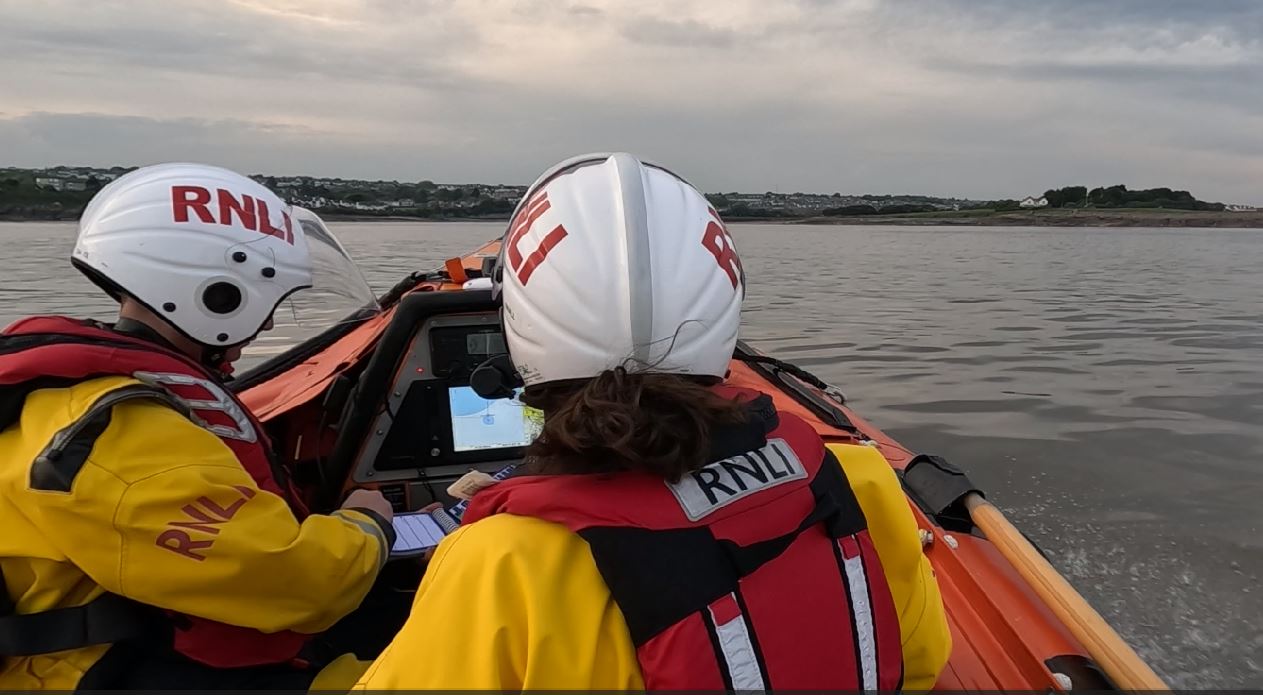 Two crew members looking at a screen to plot a course 