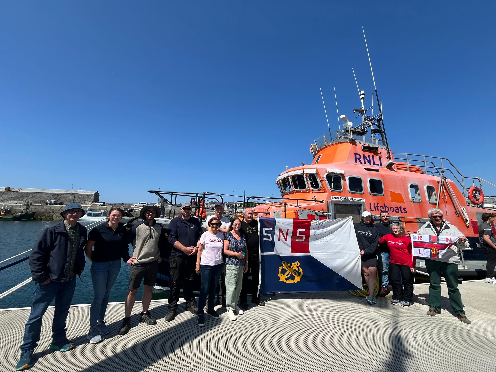 Crew of Le Biche &amp; Aran Islands RNLI holding up the RNLI flag and SNSM flag in front of the Severn Lifeboat