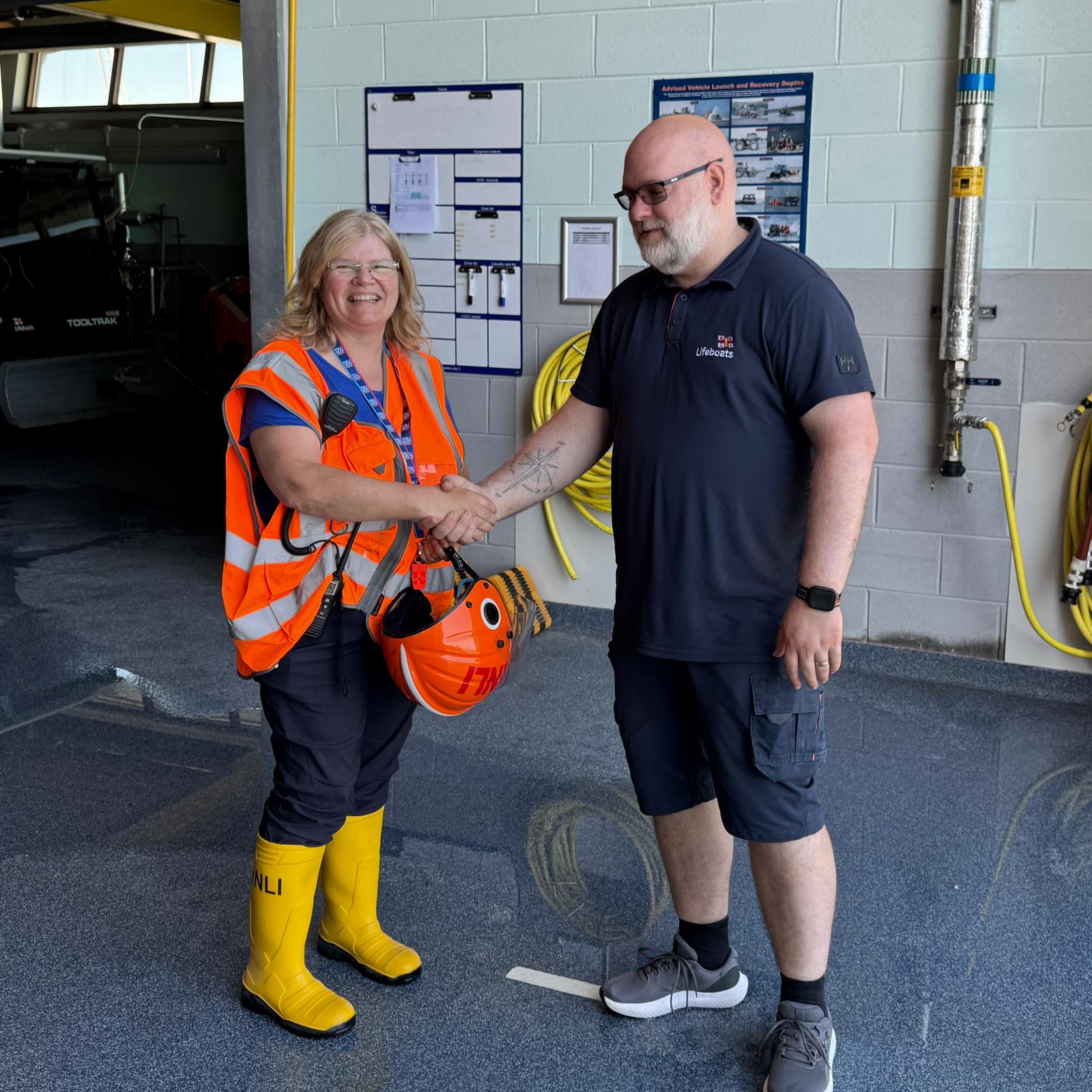 Caroline Jones shaking hands with RNLI trainer assessor following successful completion of Head Launcher training at Pwllheli RNLI