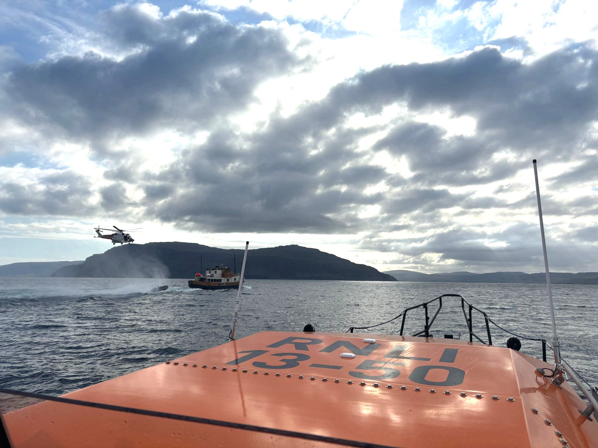 In the early morning light, a Coastguard rescue helicopter hovers above a small cruise ship in a photo taken from the Oban lifeboat.
