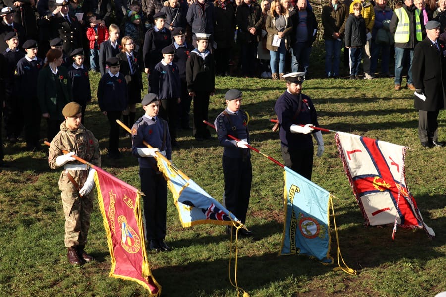 Four members of the remembrance parade hold flags on Grange Hill, West Kirby