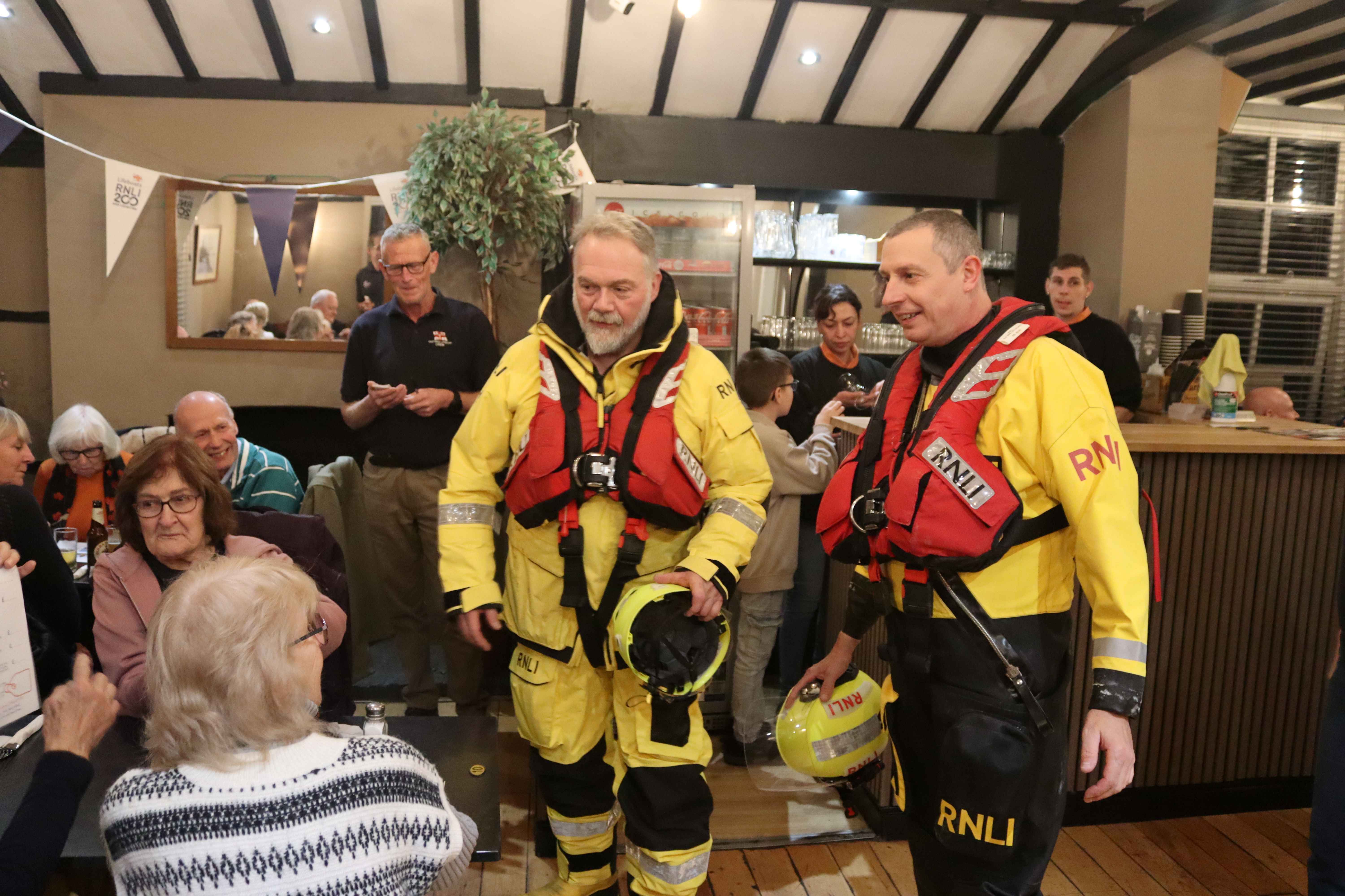 Two crew members demonstrating the yellow protective clothing they normally wear afloat