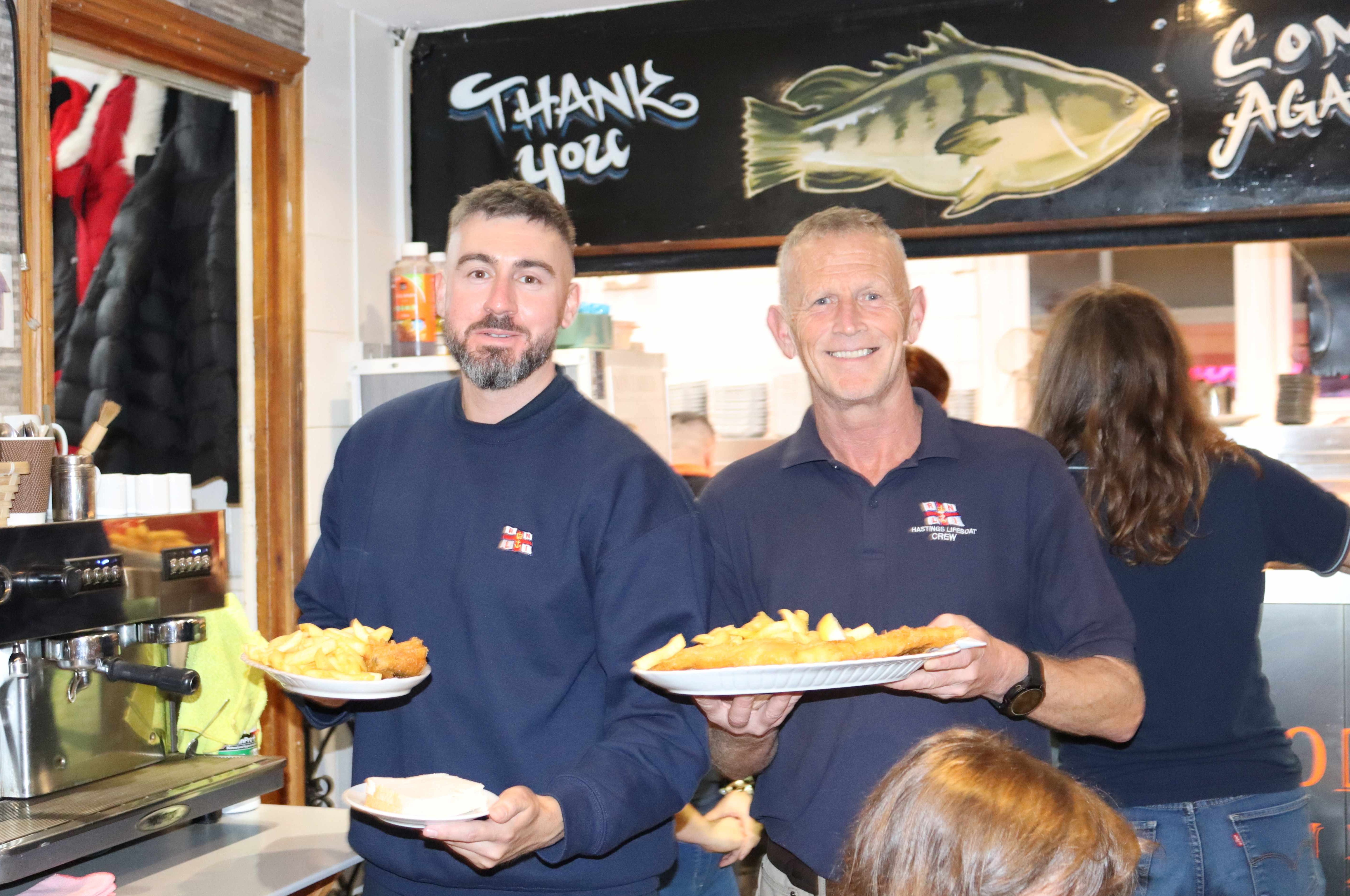 Two RNLI crew members with platefuls of food ready to serve in the restaurant