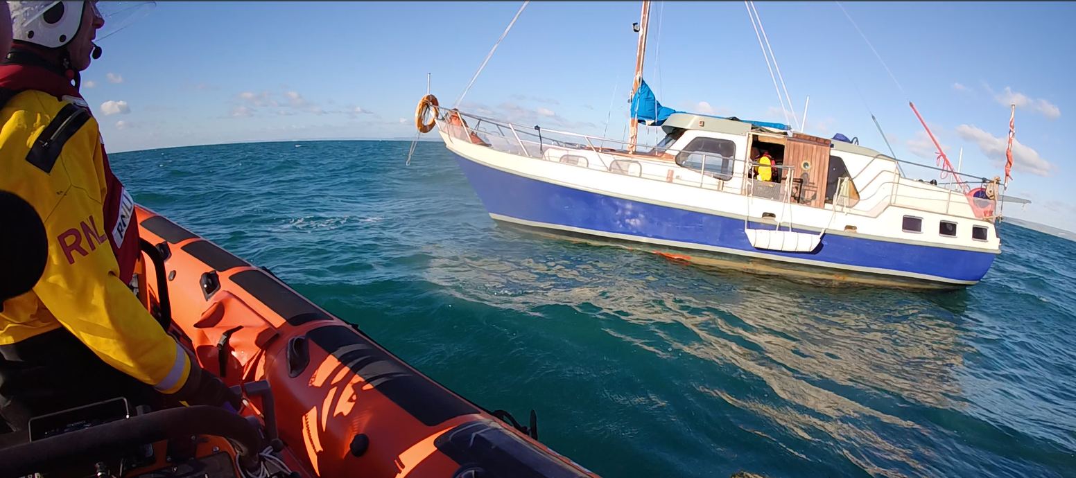 RNLI crewman in the hatchway of the disabled yacht. Picture taken from Lyme Regis lifeboat