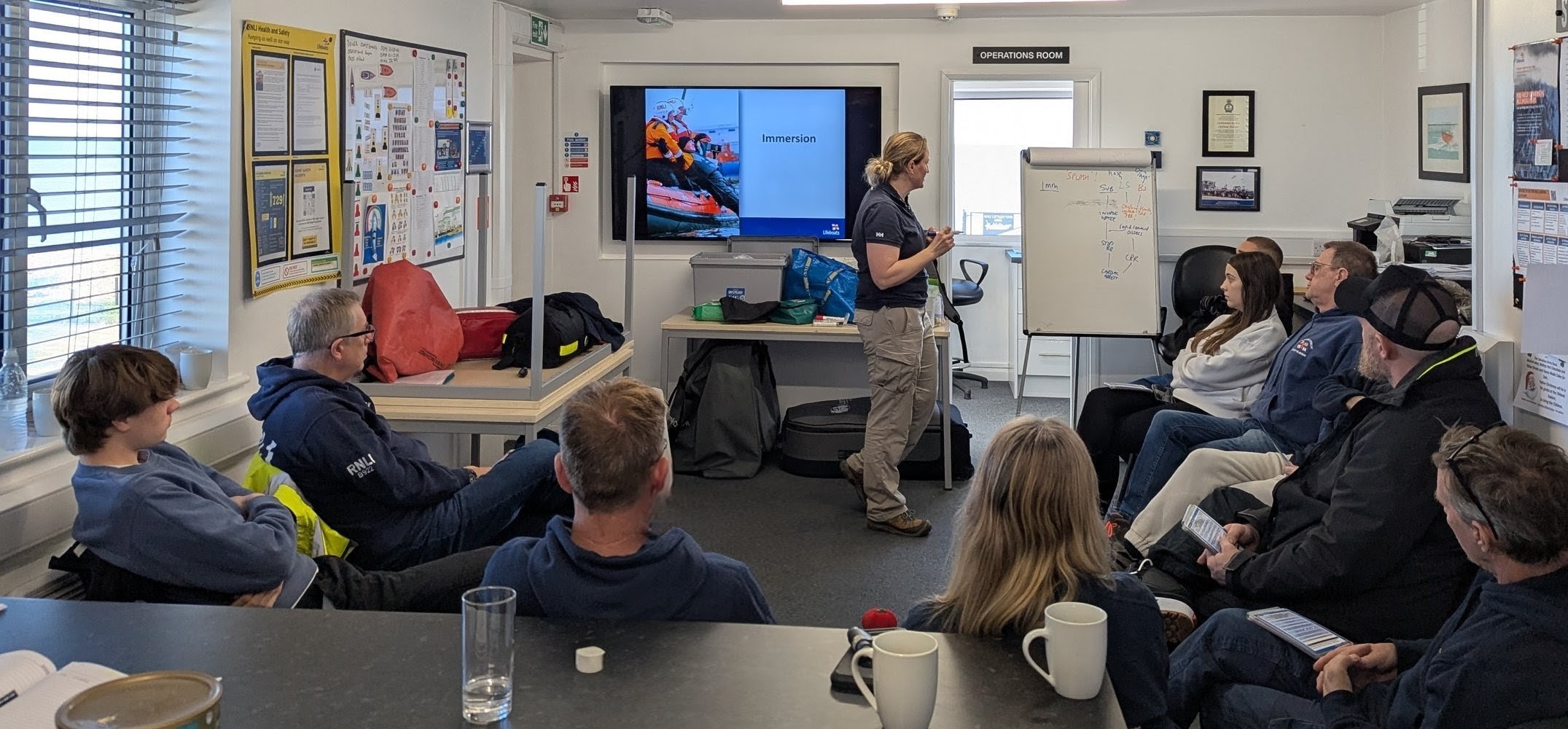 An RNLI trainer infront of a whiteboard talking about the dangers of immersion in water
