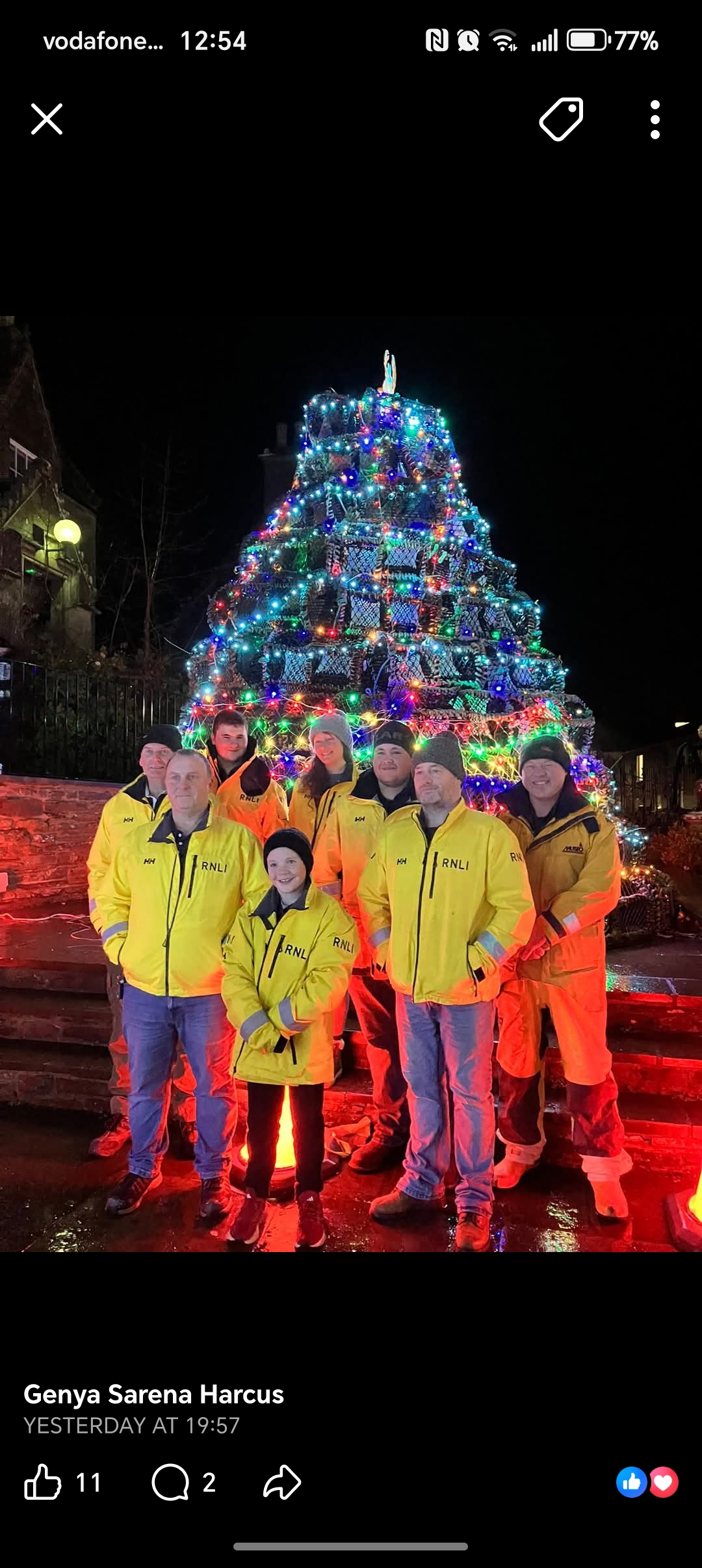 Illuminated tree of creels with crew standing in front