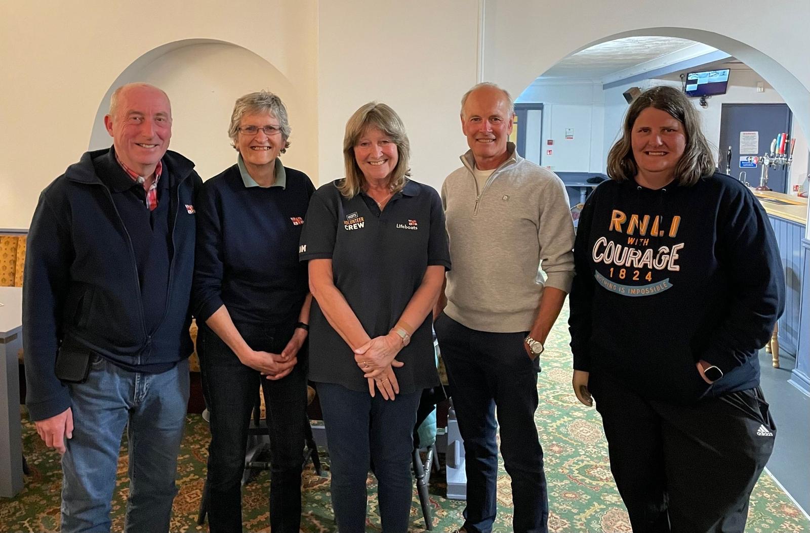 male and female memebers of Wells RNLI in branded clothing standing posed for a photo at a Dabbling Duck quiz night
