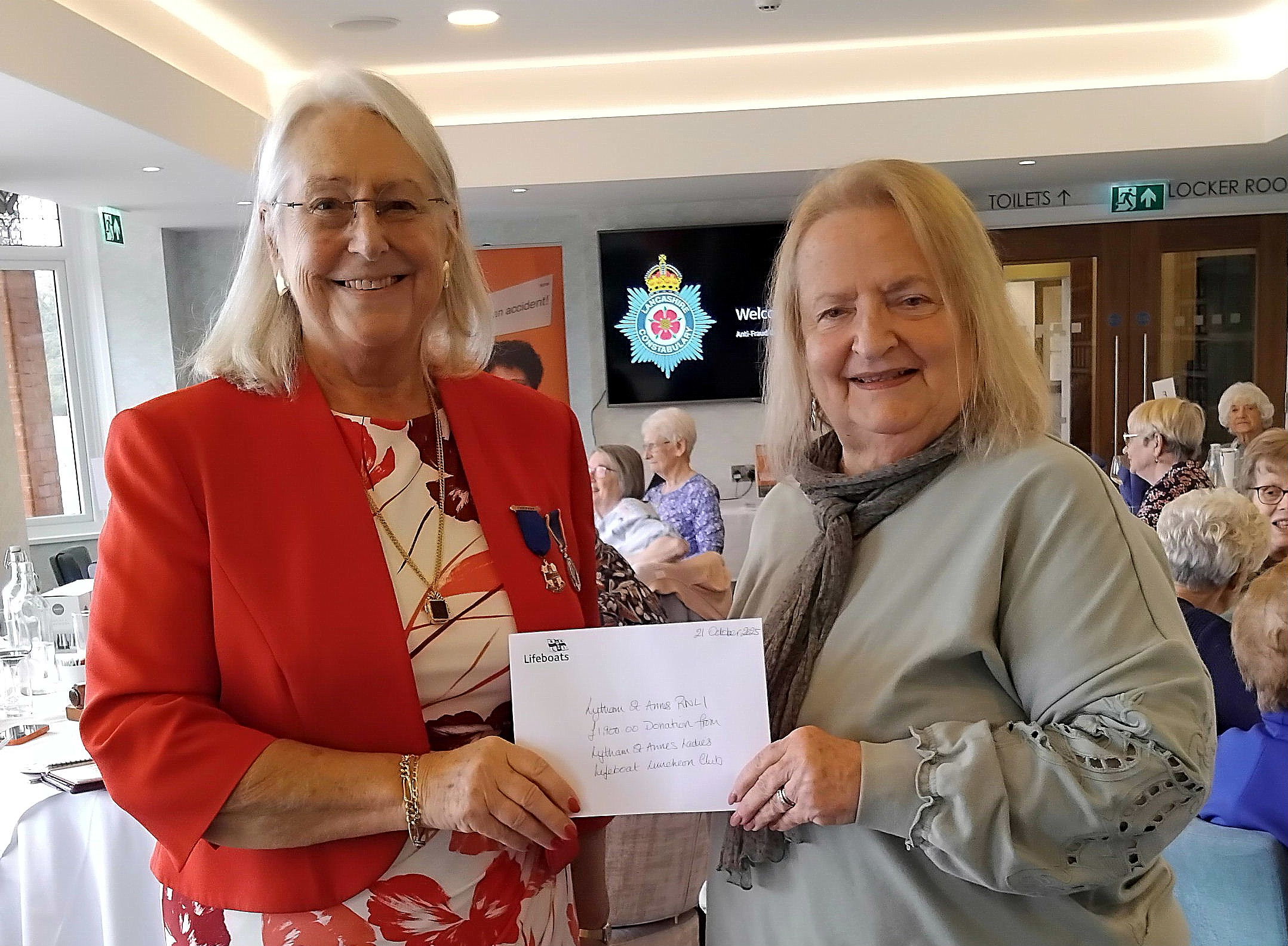 Two ladies hold a donation cheque 