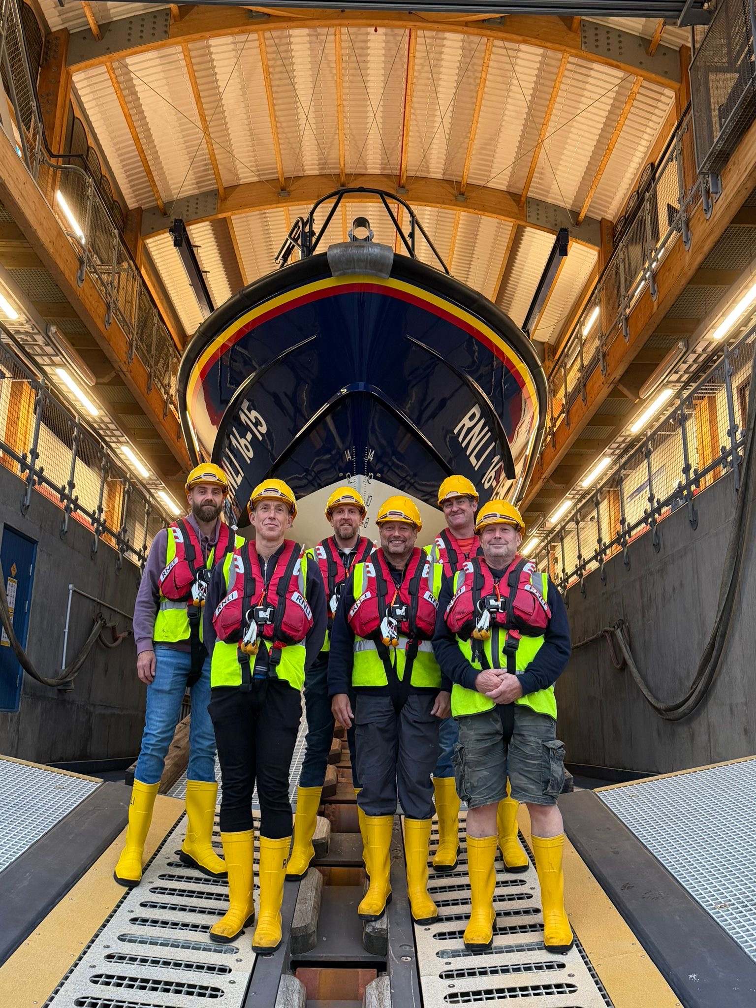 Six shore crew members stand in front of Shoreham RNLI's all weather lifeboat