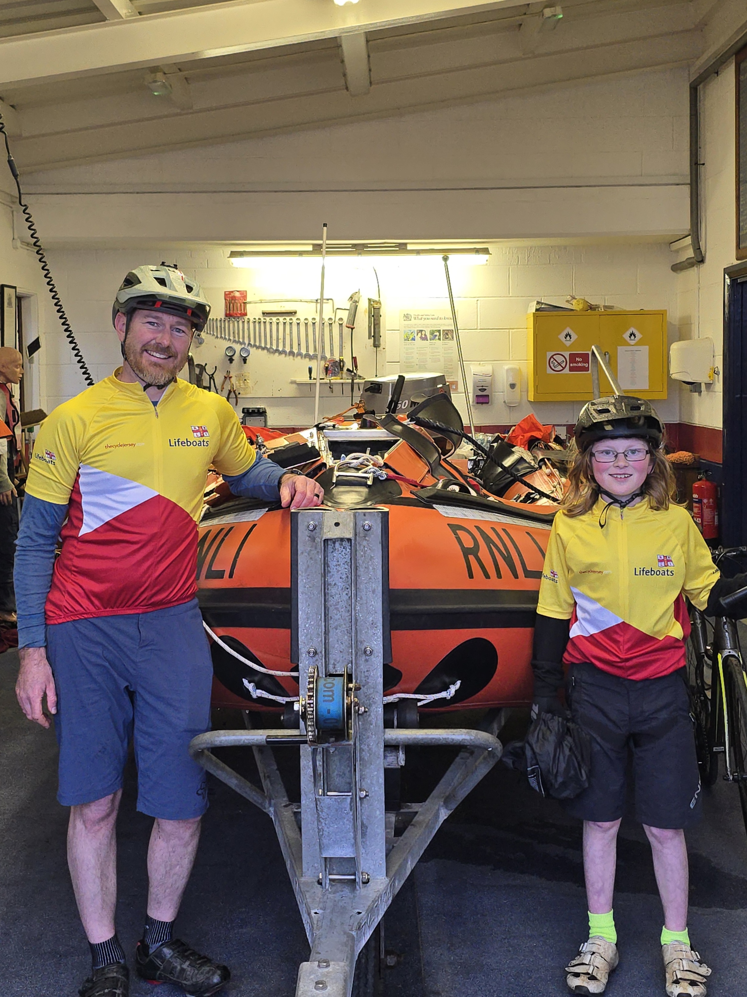 Ten-year-old Henry Warwick and his father Hugh in front of Fishguard RNLI D class inshore lifeboat Edward Arthur Richardson following completion of their cycle for the RNLI.