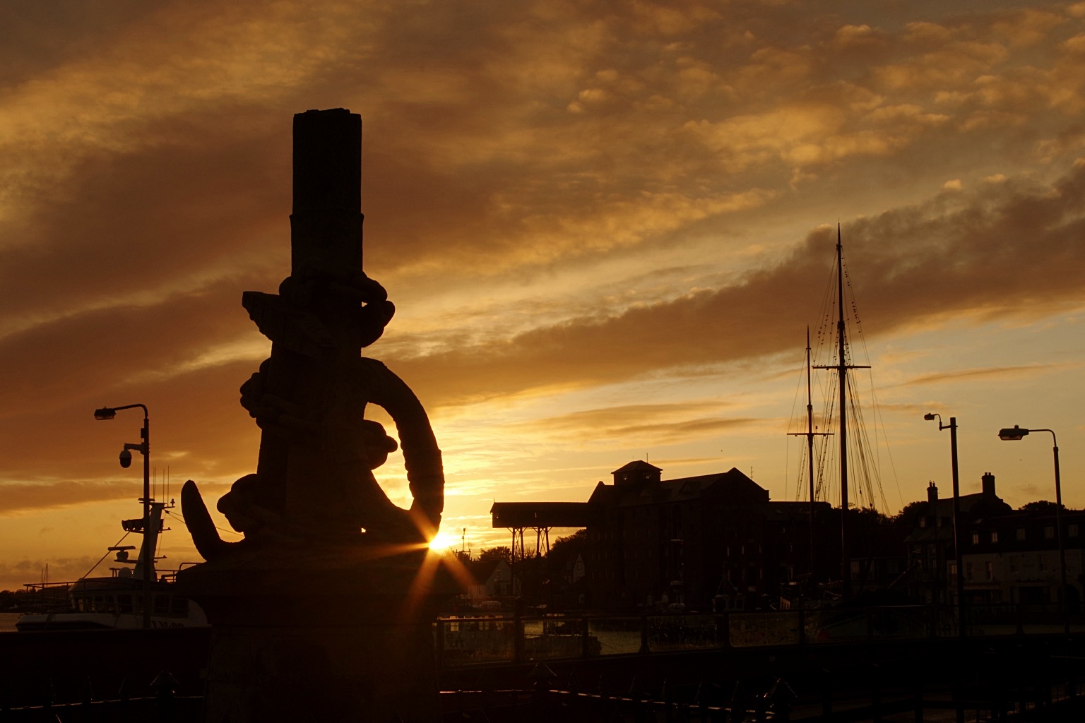 Memorial with sun rise behind making it a silhouette of the memorial and town