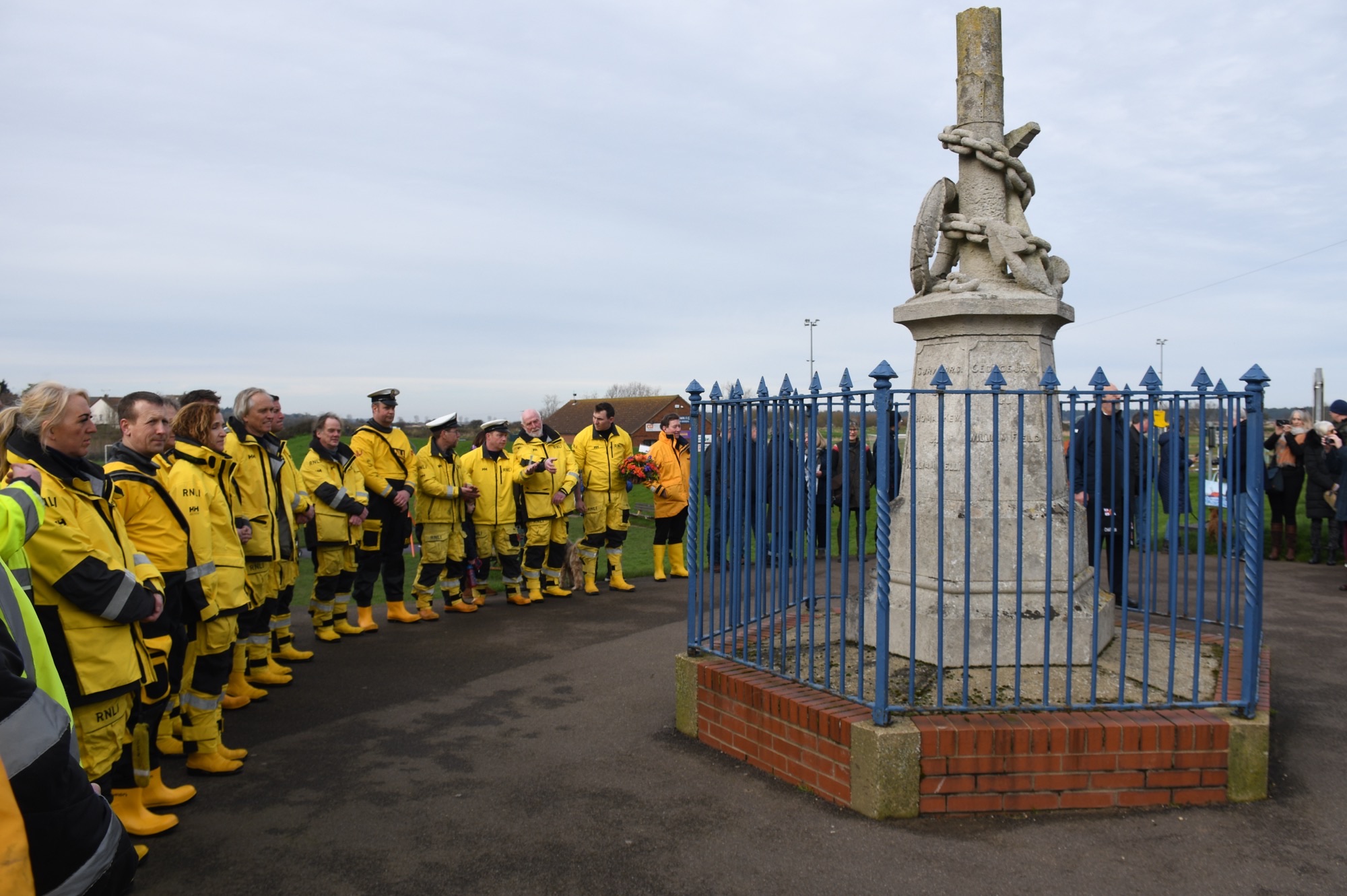 Wells RNLI crew pay tribute during 200th anniversary of RNLI celebrations to the brave crew of the Eliza Adams. Crew members in full yellow RNLI kit standing around the memorial

