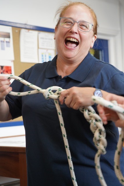A woman holds up a rope tied with a knot, smiling