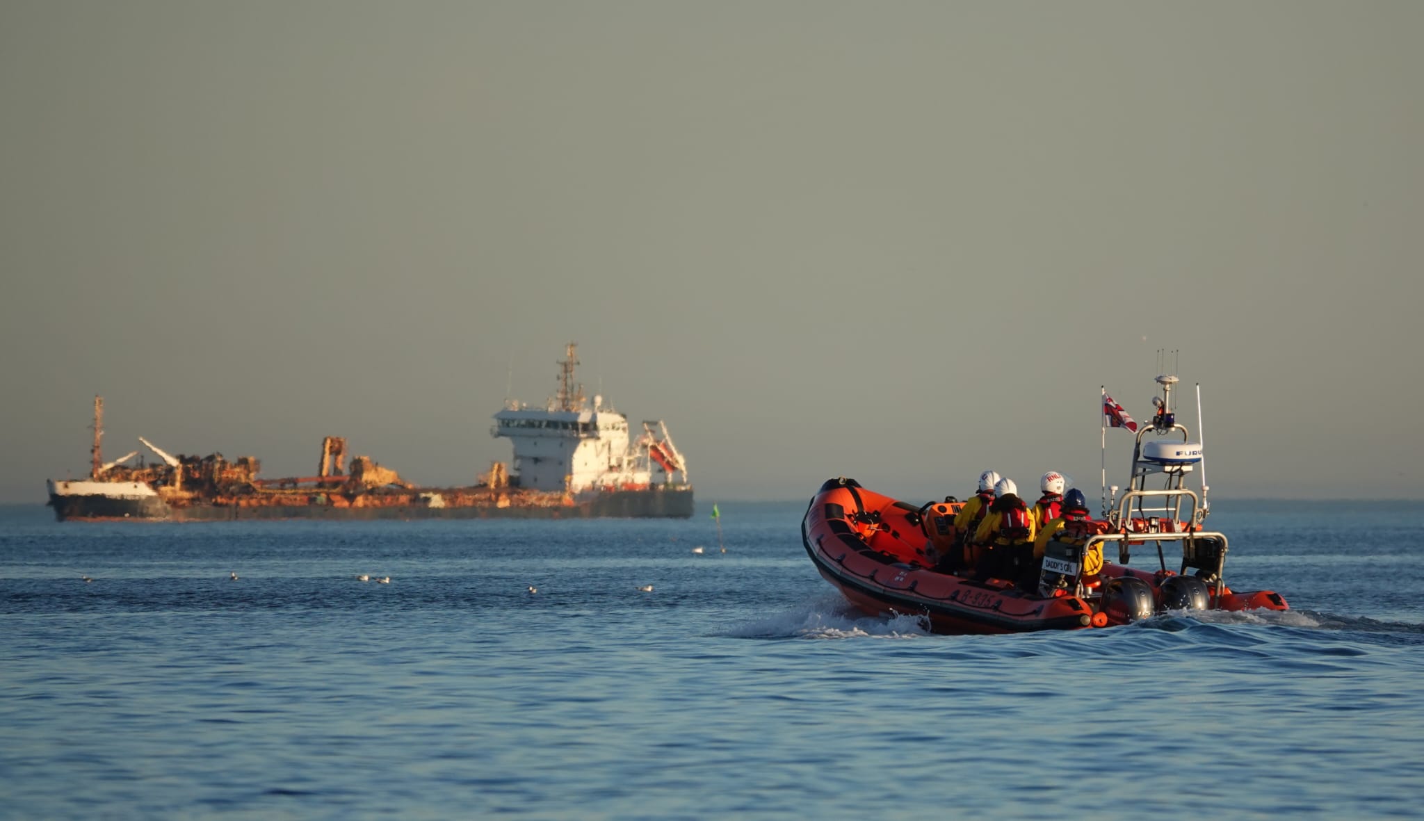 Lifeboat heads out of the bay towards a cargo vessel at anchor