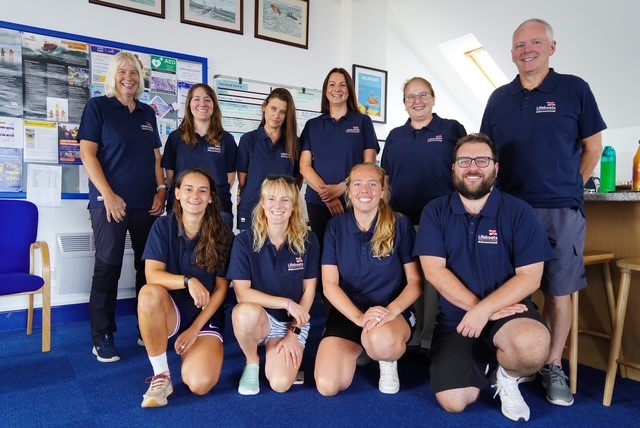 A group of people in RNLI t-shirts in a lifeboat station