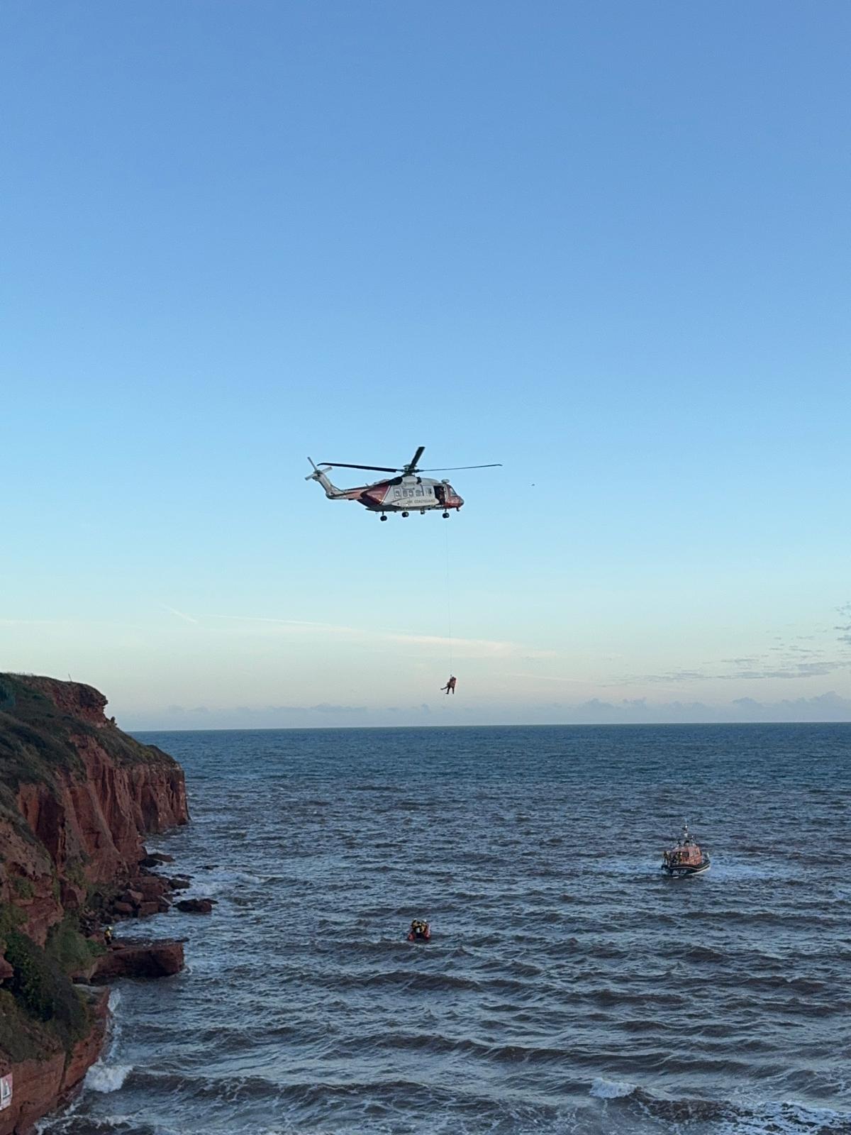 Exmouth RNLI Inshore and All-weather lifeboats working alongside H.M. Coastguard helicopter to extract casualties on rocks