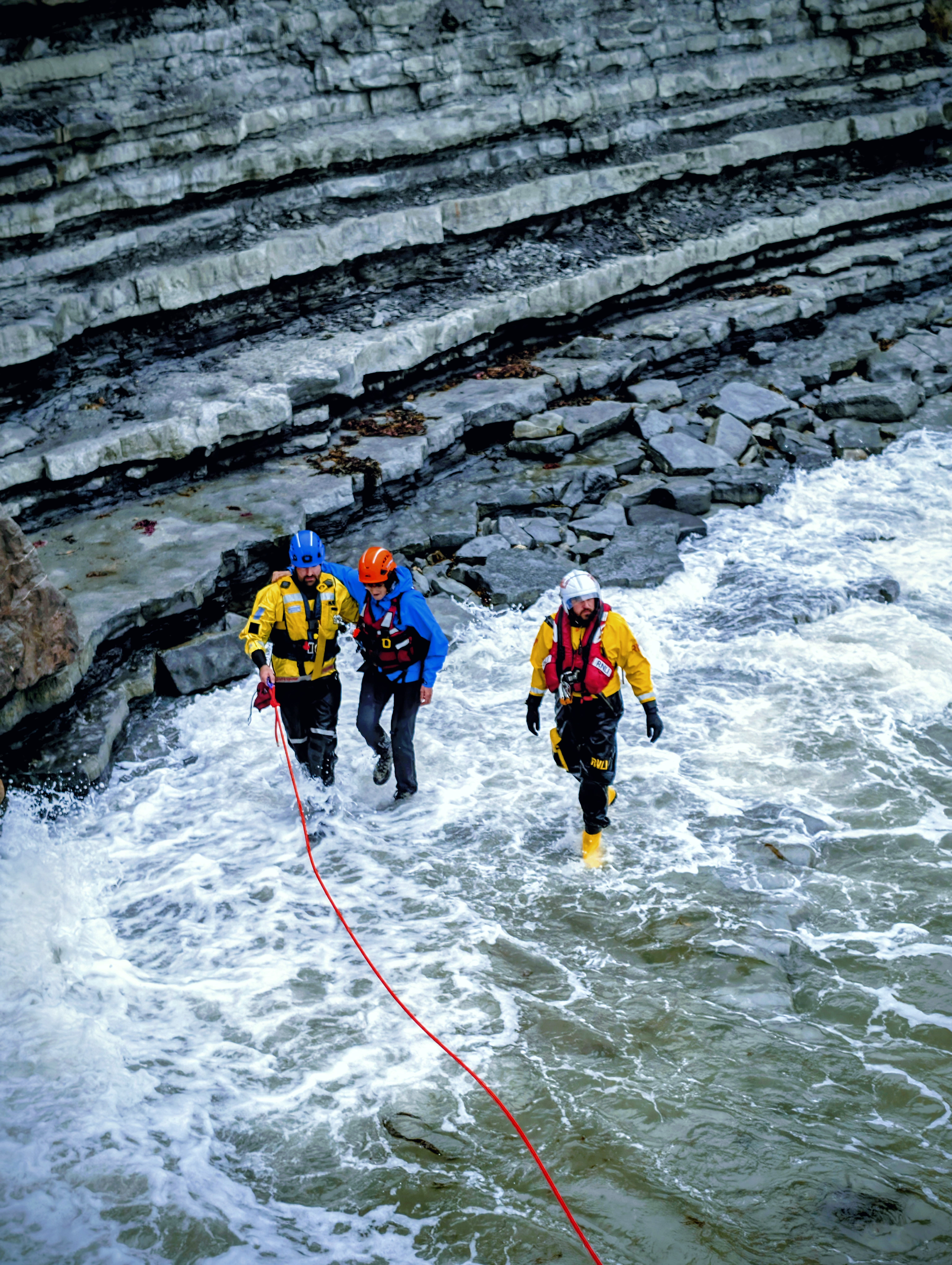 3 figures moving through surf