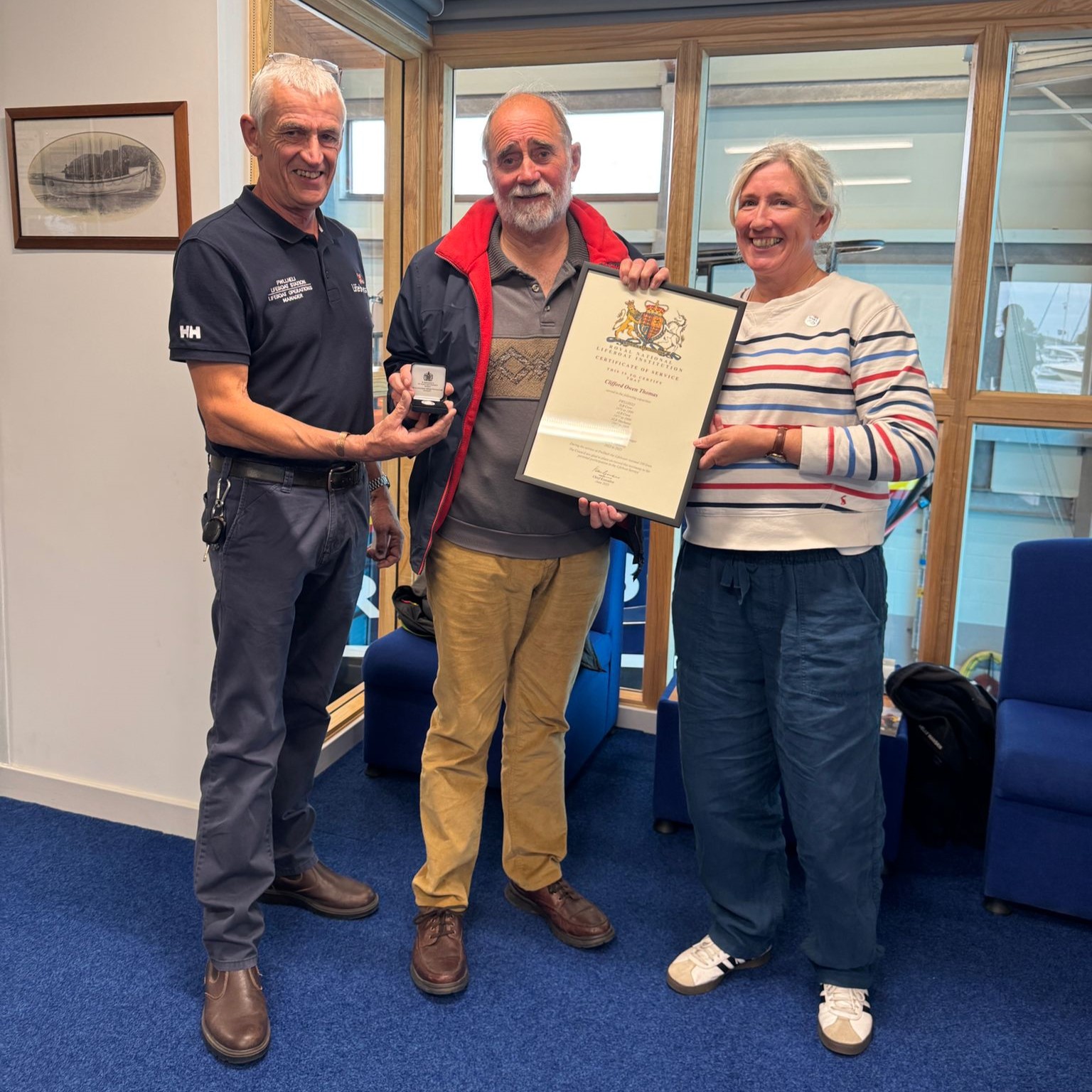 Cliff Thomas being awarded medal and certificate for 50 years volunteering service at Pwllheli RNLI. From left to right in the photo, Andy Vowell, Pwllheli RNLI Lifeboat Operations Manager, Cliff Thomas and Carolyn Greene, RNLI Chief People Officer.