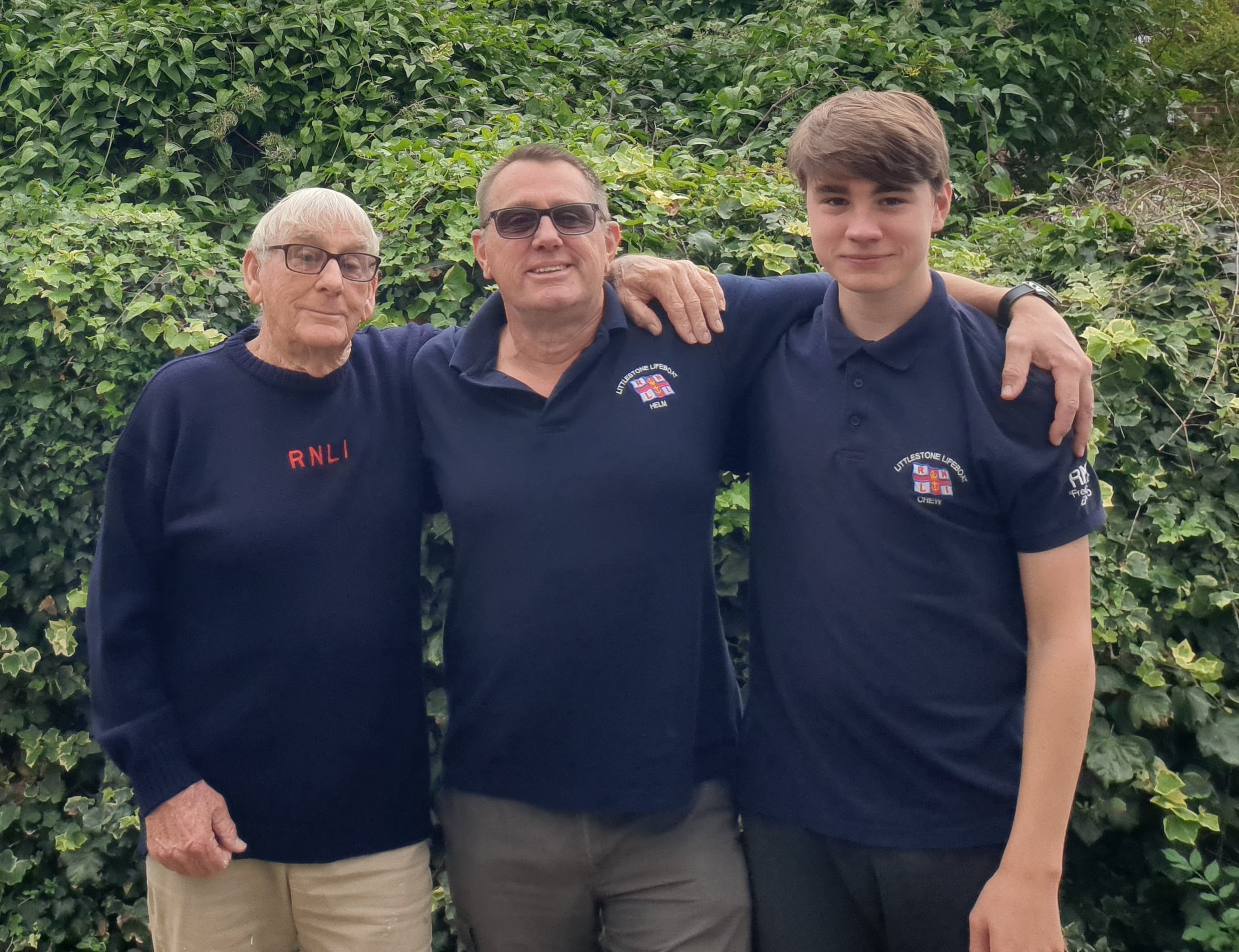 Three people in RNLI branded sweaters with Pat Leigh, Peter Leigh and Samuel Leigh.