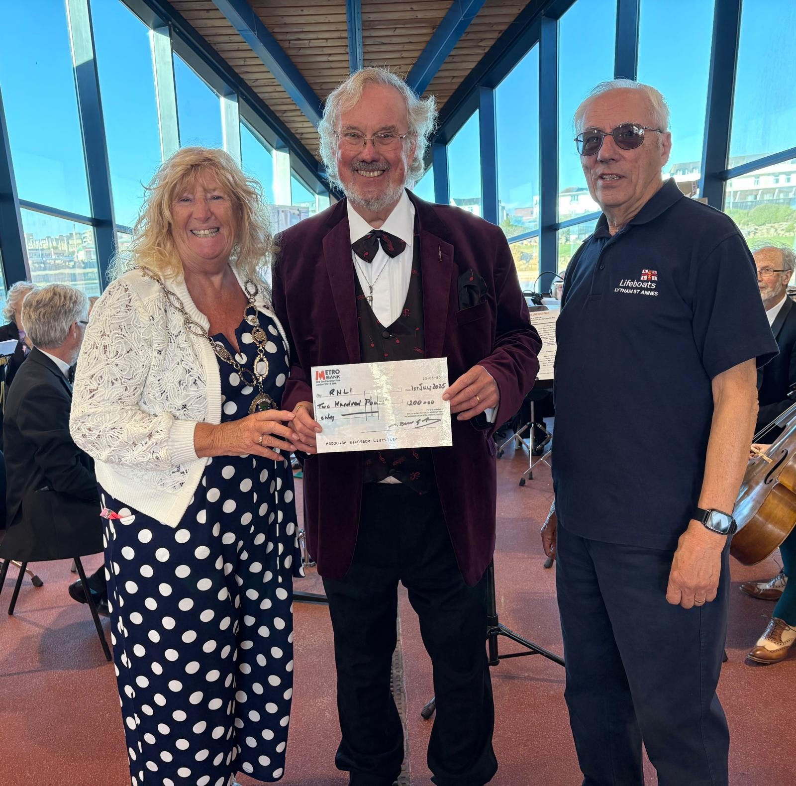 three people hold a cheque being presented to the RNLI
