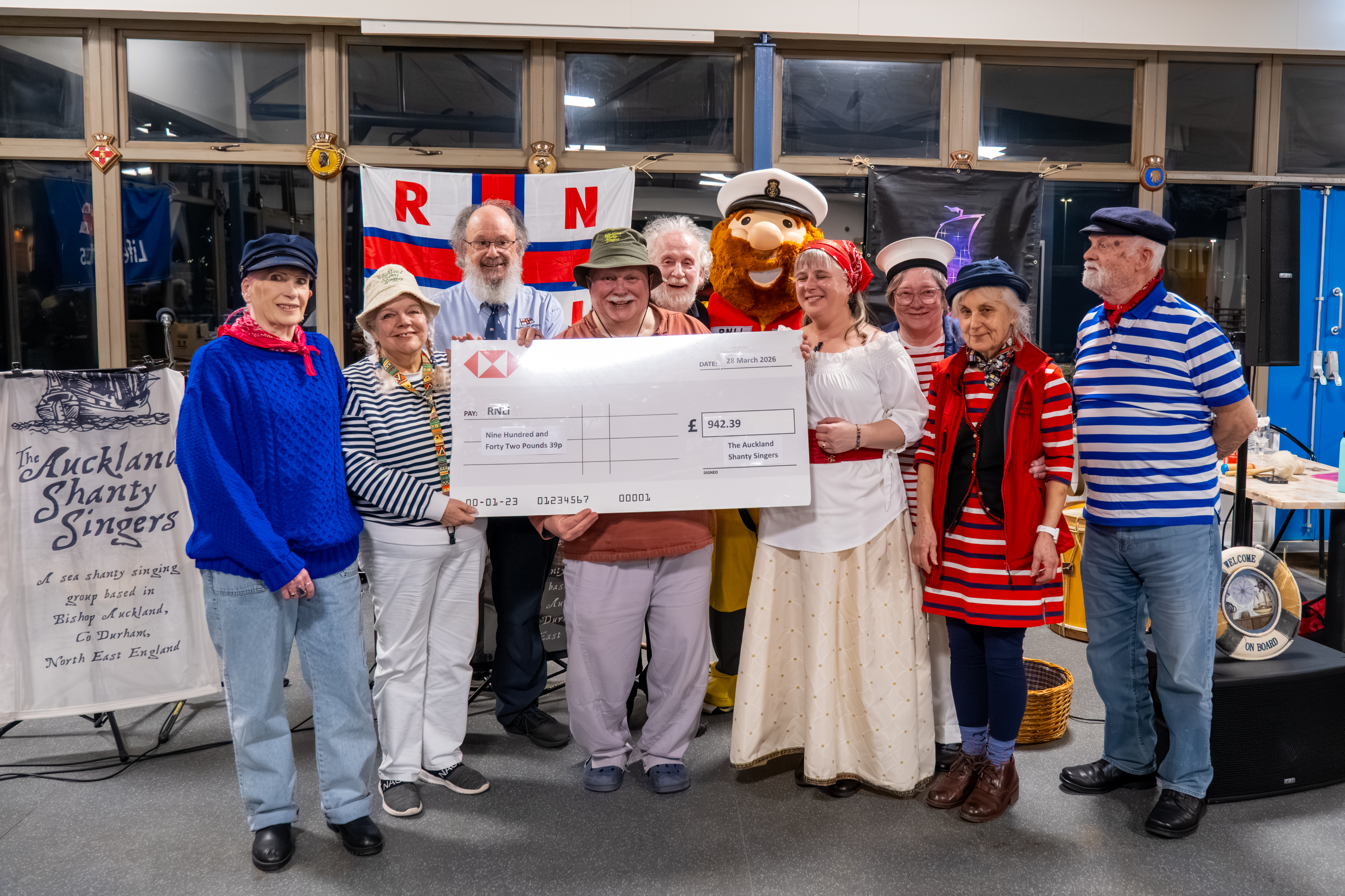 This image captures a proud and celebratory moment from the evening, centred around the presentation of a donation to the RNLI
