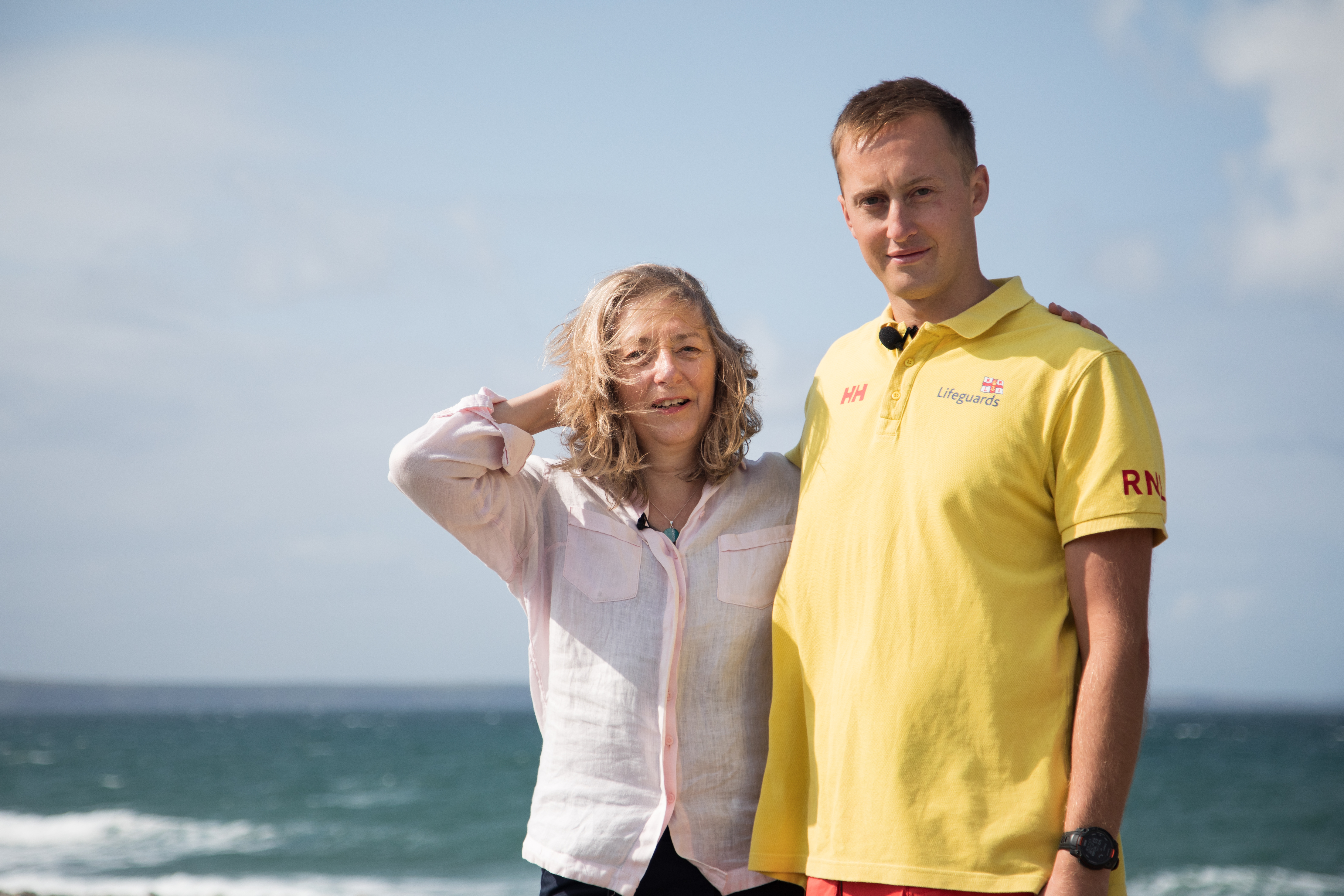 Landscape image of Matty and Joanna facing the camera with backdrop of the sea.