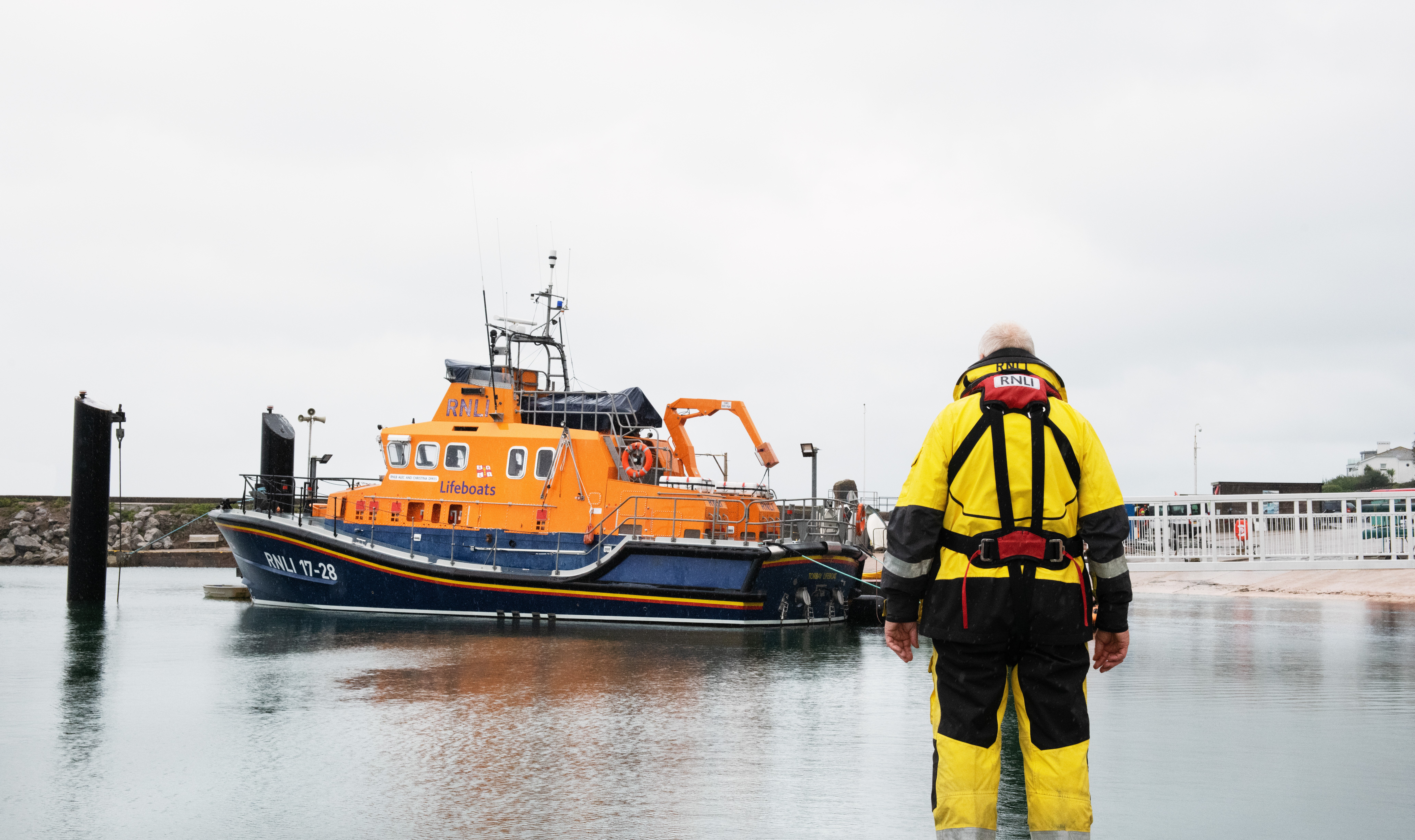 Torbay RNLI's Severn-class All-Weather lifeboat moored at Torbay Lifeboat Station in Brixham with volunteer crew member looking onat T