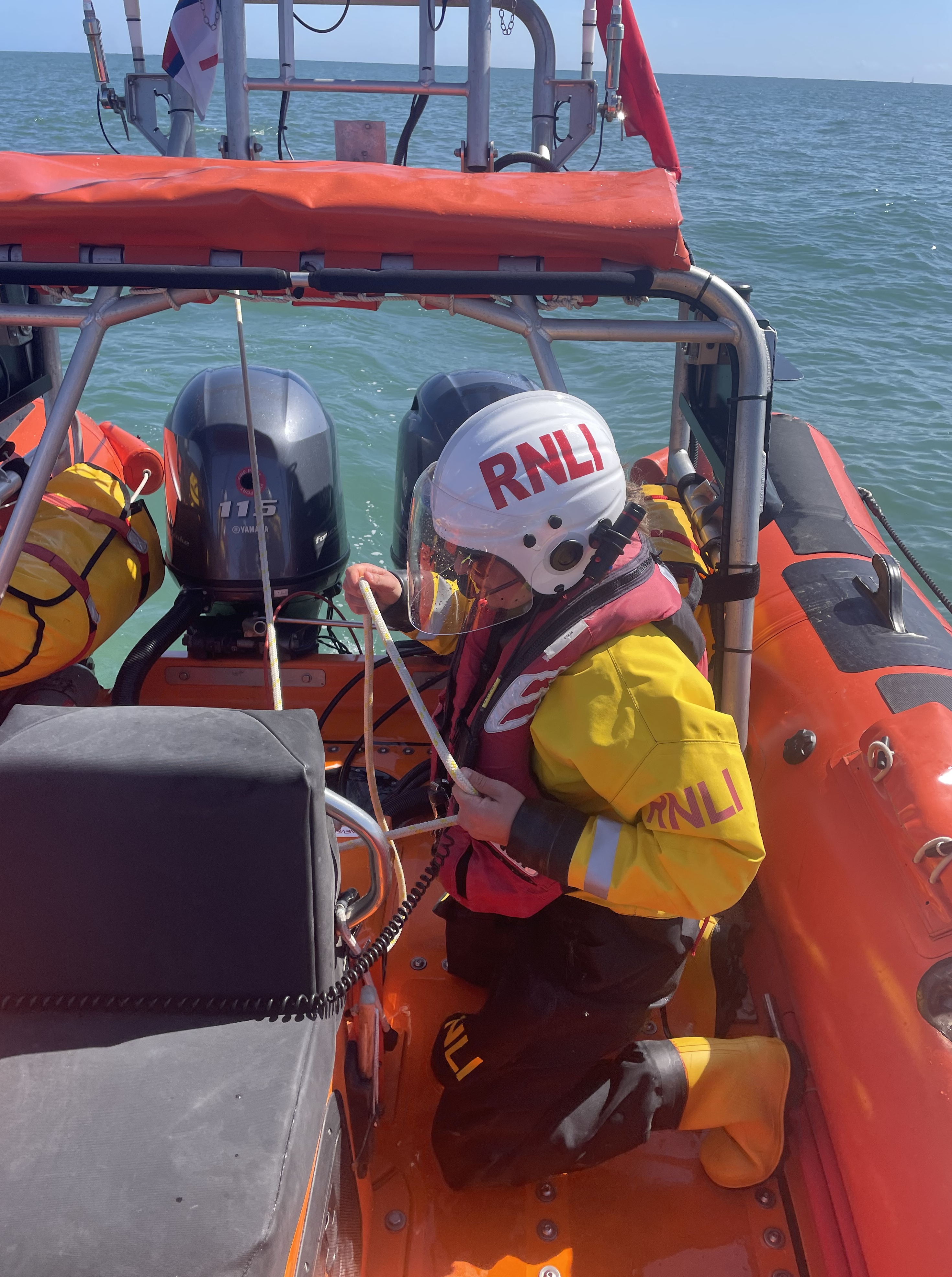 Miheala kneeling down on lifeboat with rope in her hands